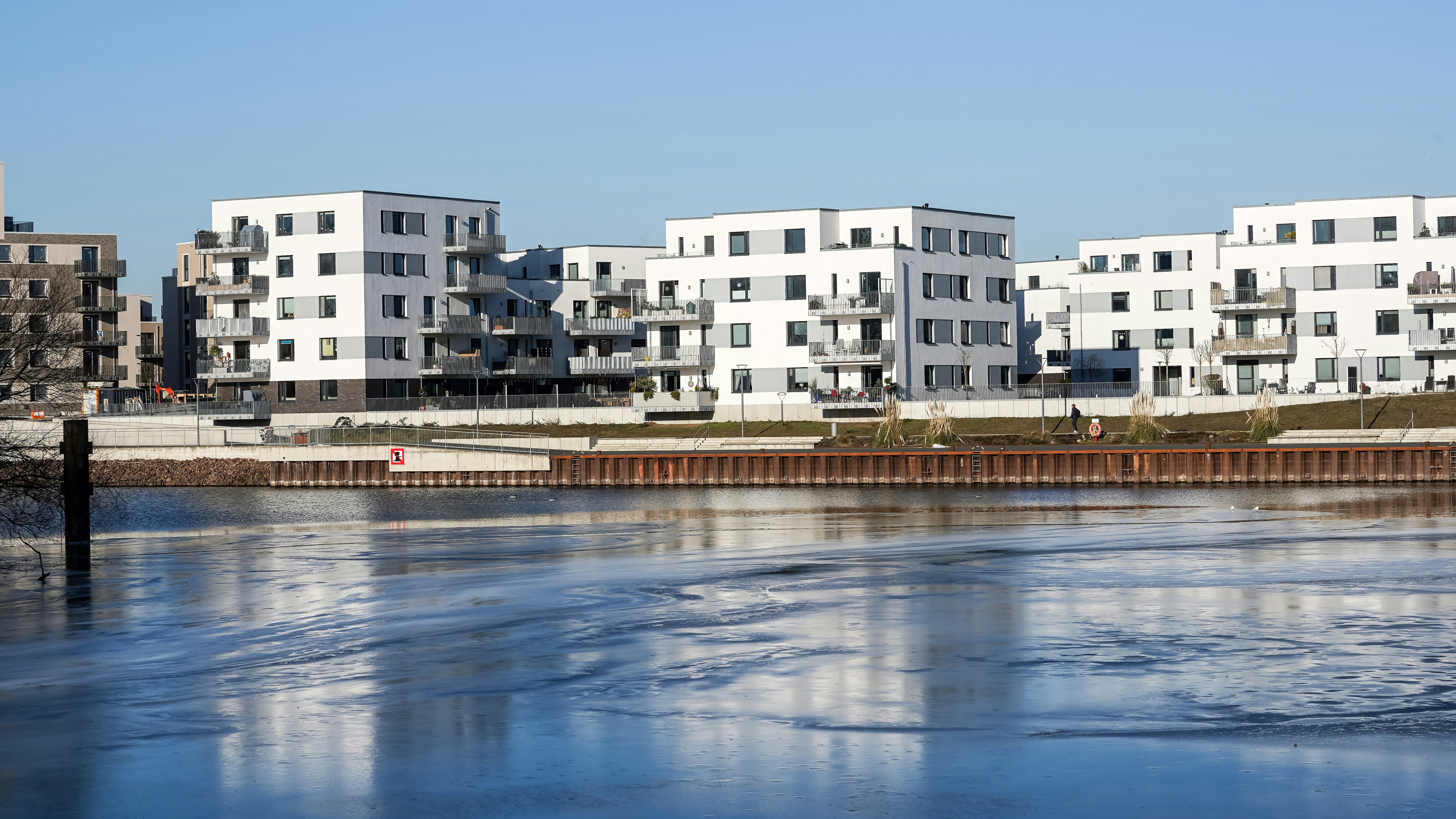 Modern white apartment buildings by a reflective river