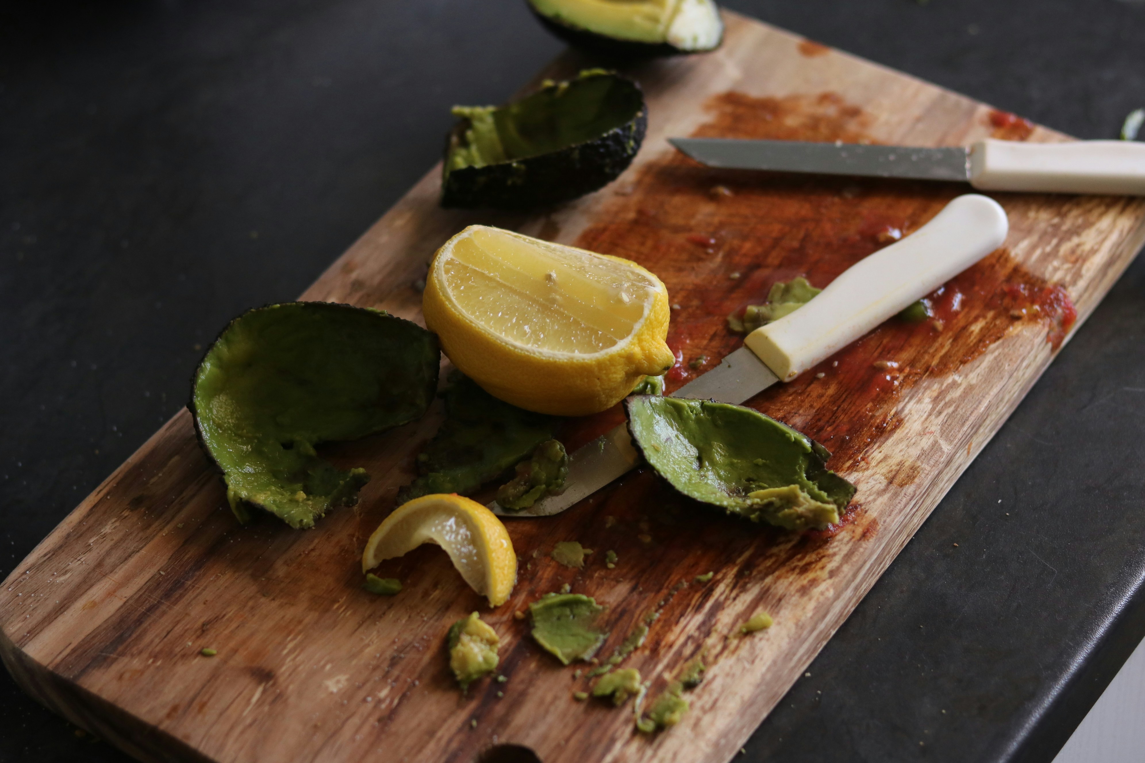Avocado and lemon scraps on a wooden cutting board.