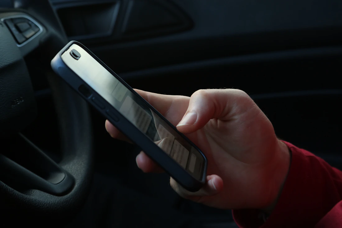 Hand holding a smartphone inside a car