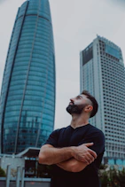 Man looking up between modern skyscrapers
