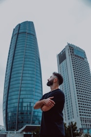 Man standing with arms crossed near modern skyscrapers