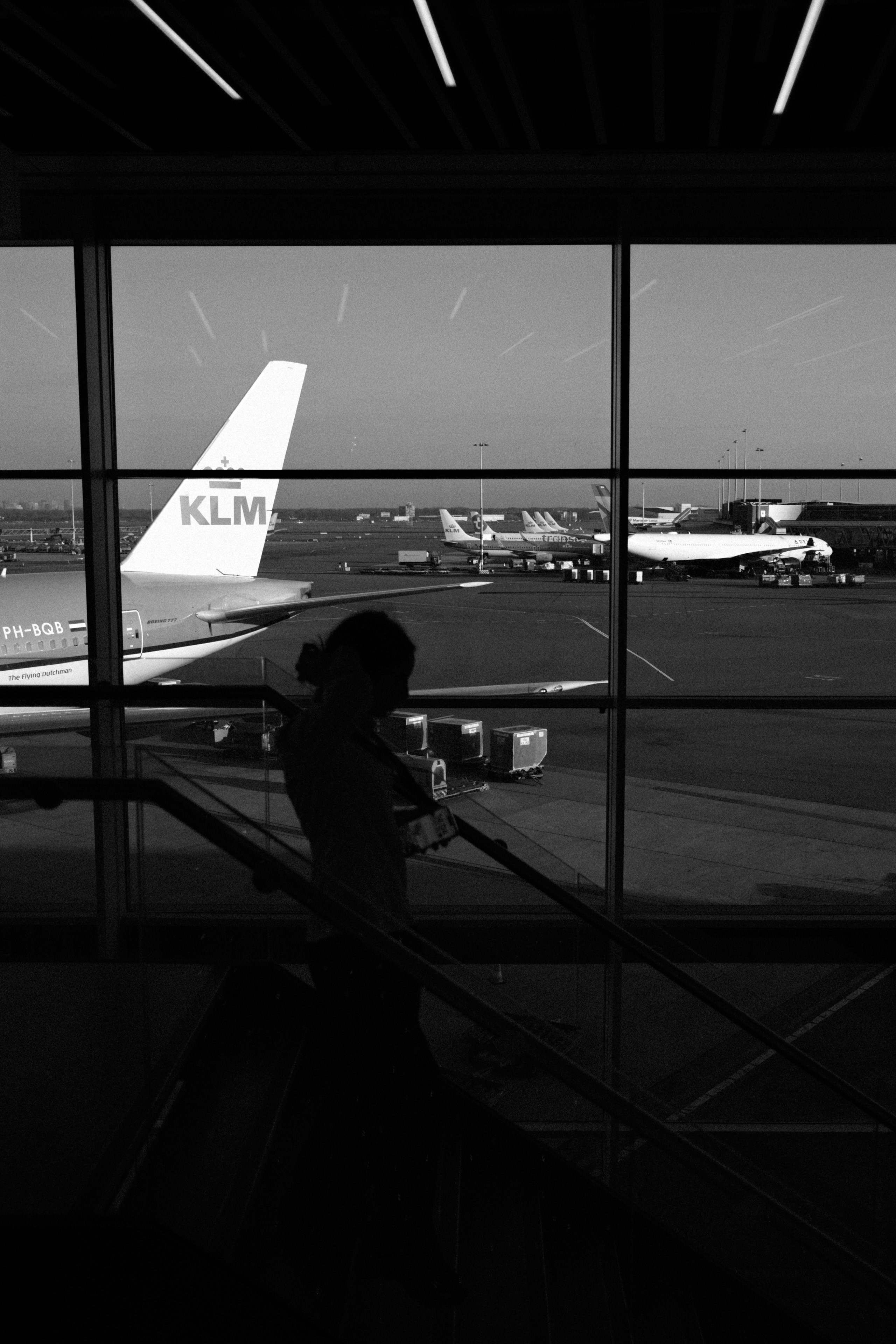 Person looking out airport window at airplanes