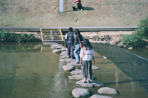 People walk across stepping stones over water