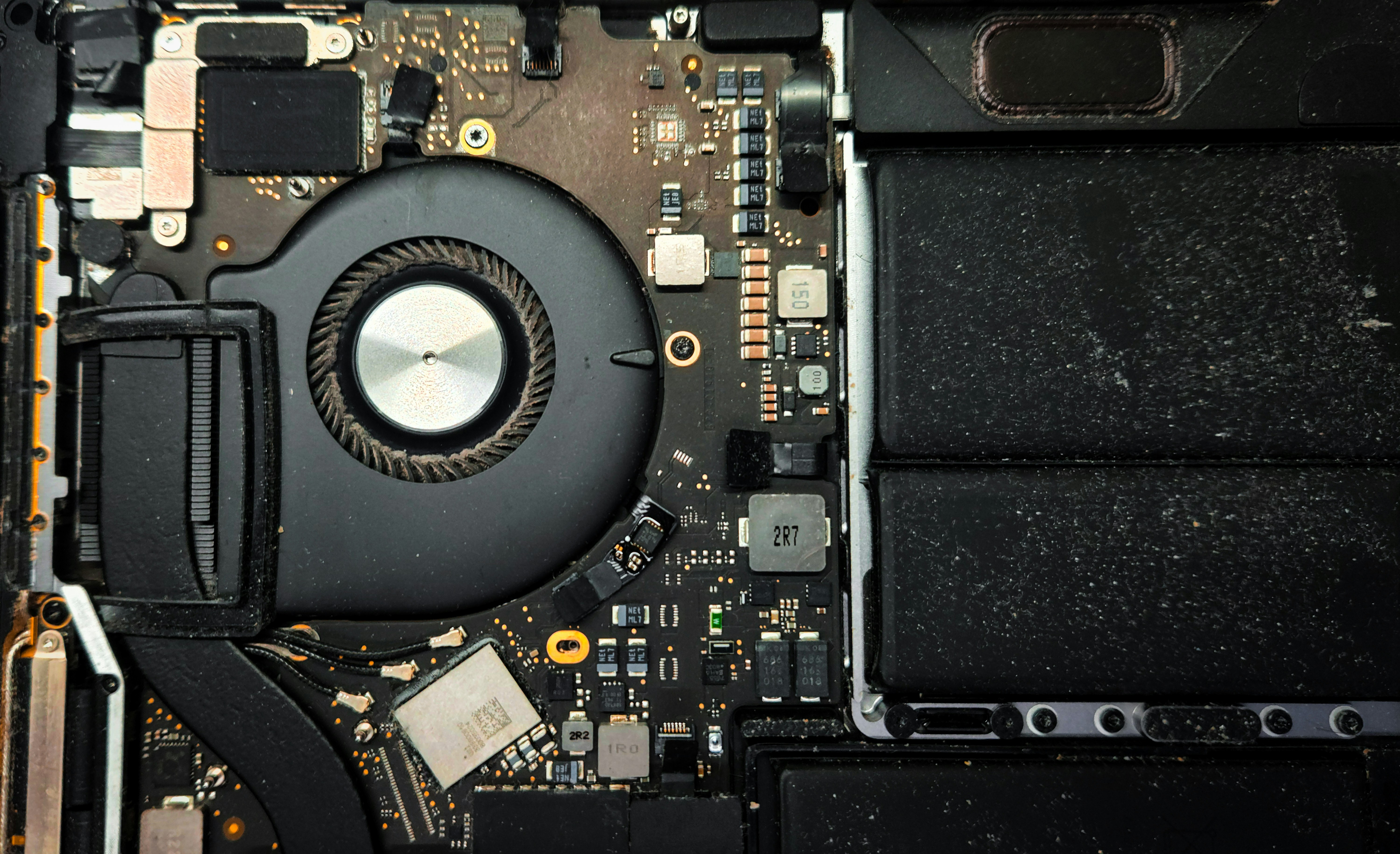 Internal view of a MacBook Pro showing the cooling fan logic board, highlighting electronic components power management chips and thermal design inside a modern laptop.