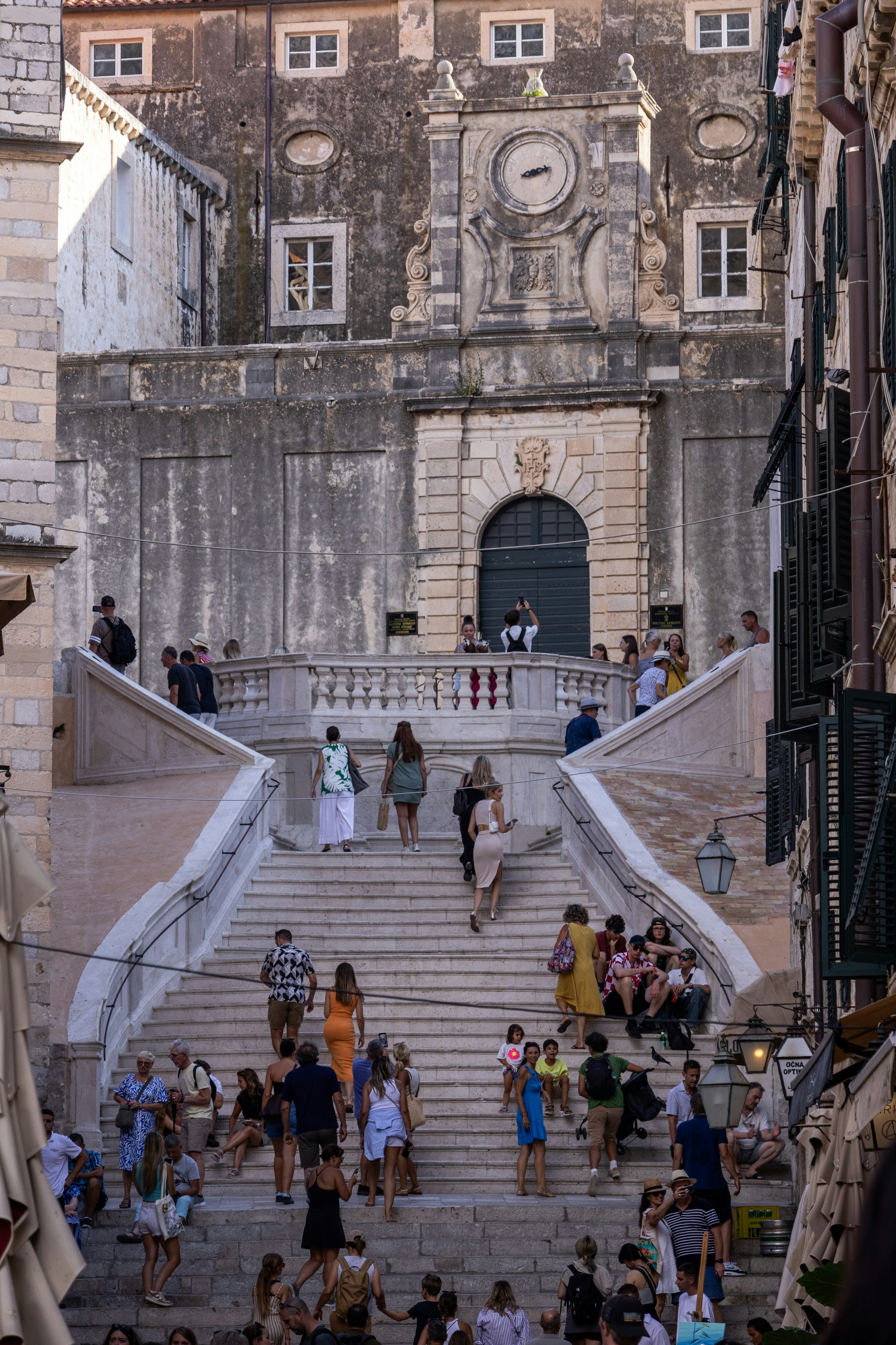 People ascend grand stone stairs towards an old building.