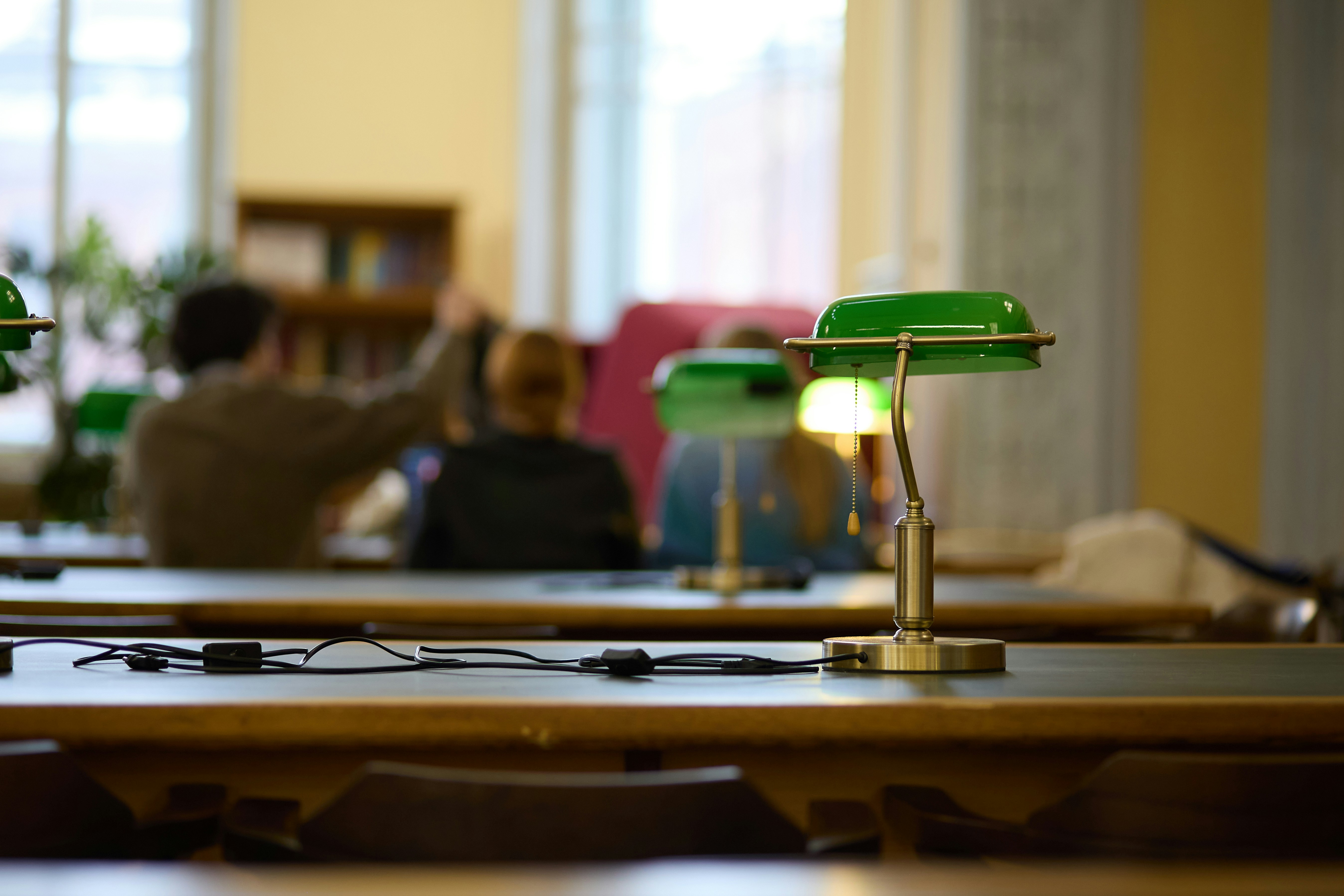 Green desk lamps on tables in a library