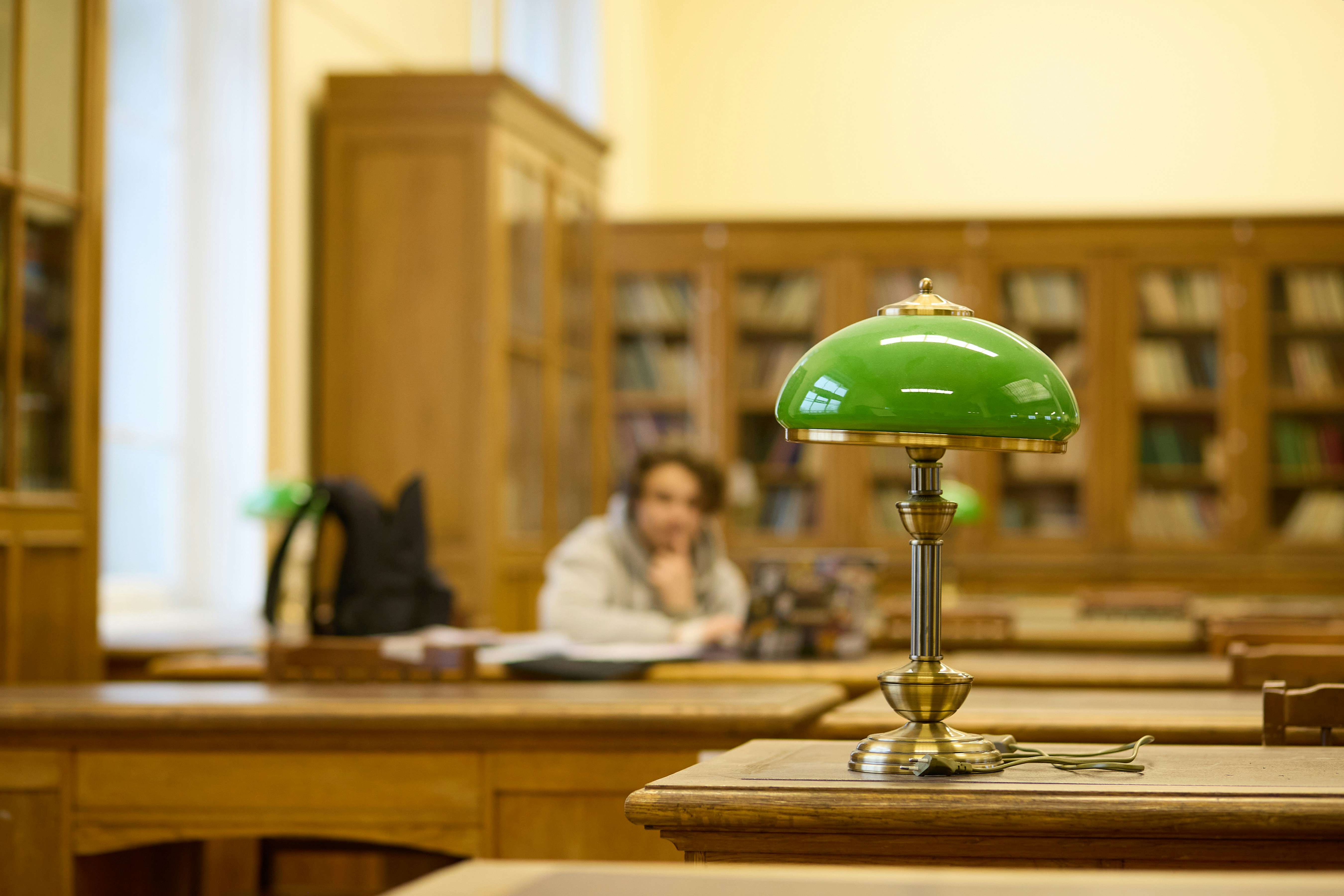 Green desk lamp on wooden table in library