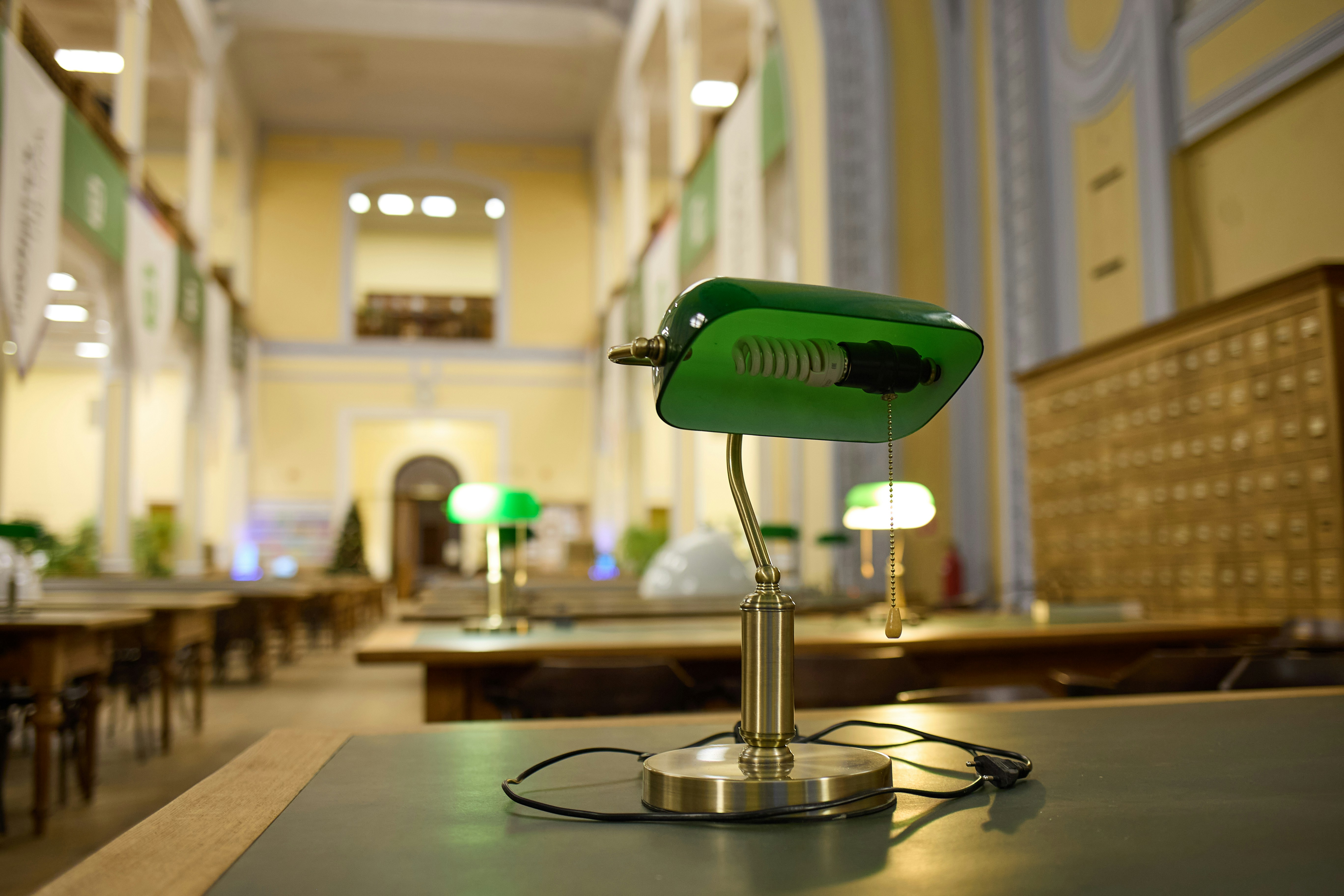 A green desk lamp in a library