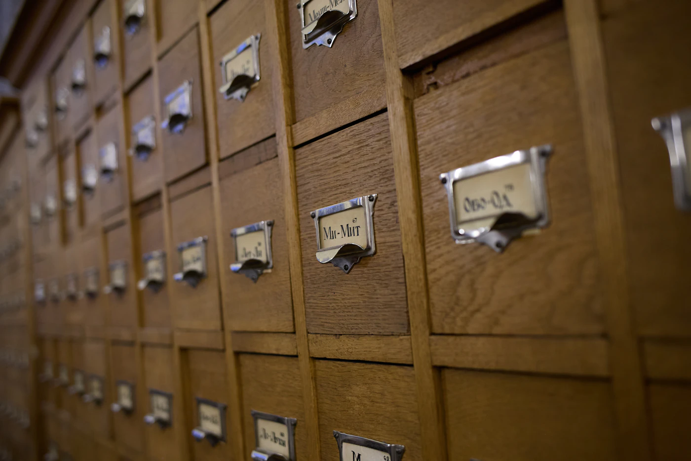 Rows of wooden card catalog drawers with small metal label holders in soft light