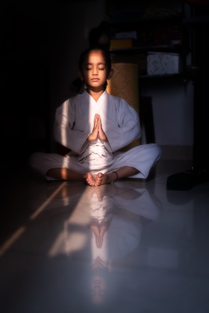 A young girl meditating in a white robe.