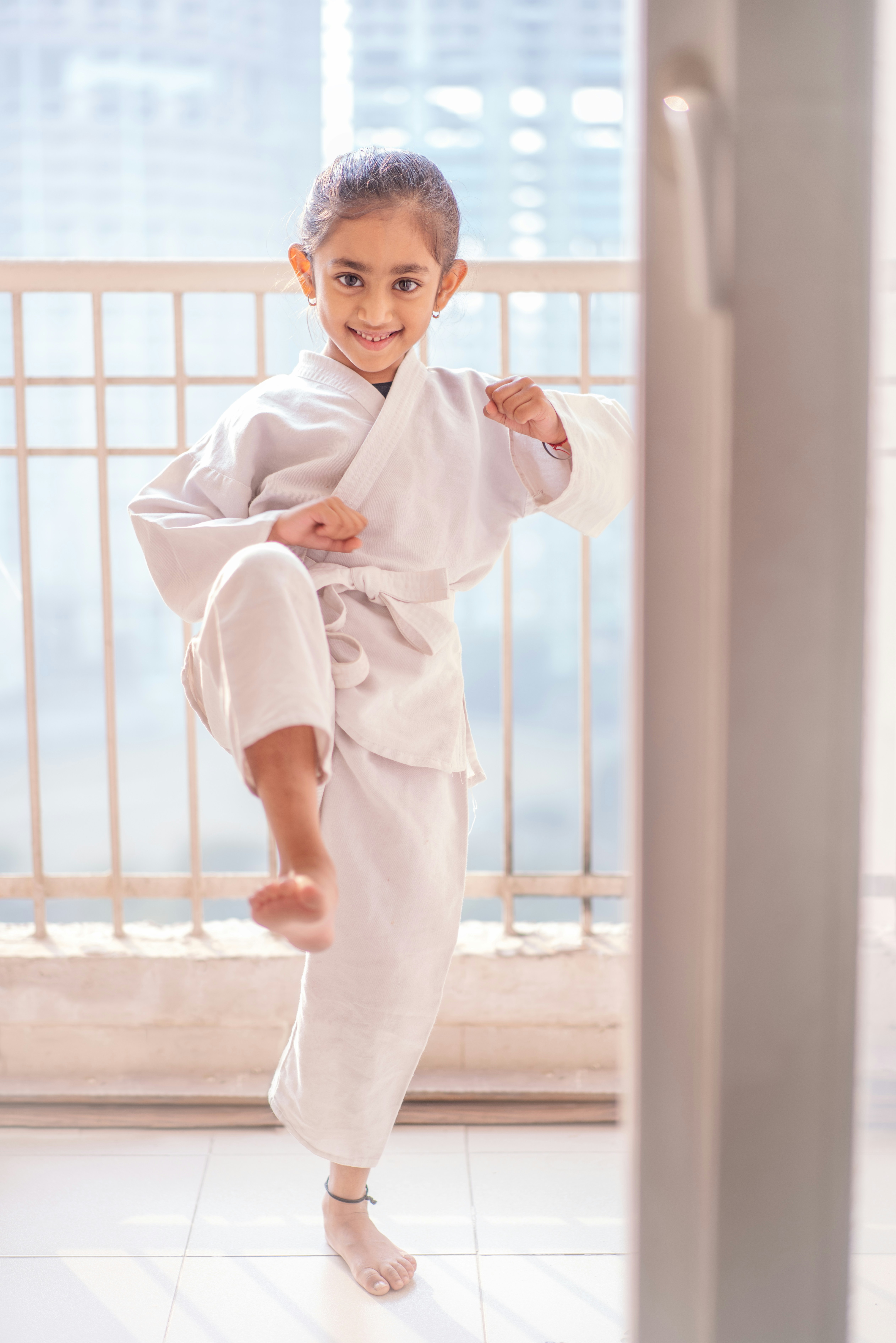 Young girl in a white karate uniform practicing a kick