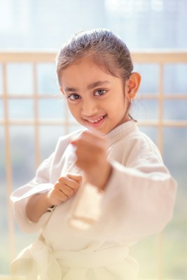 Young child in a white karate uniform with fists raised, Little Dragons karate class