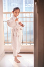 A young girl in a white karate gi smiles.