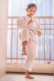 Young girl in white karate uniform practicing a stance.
