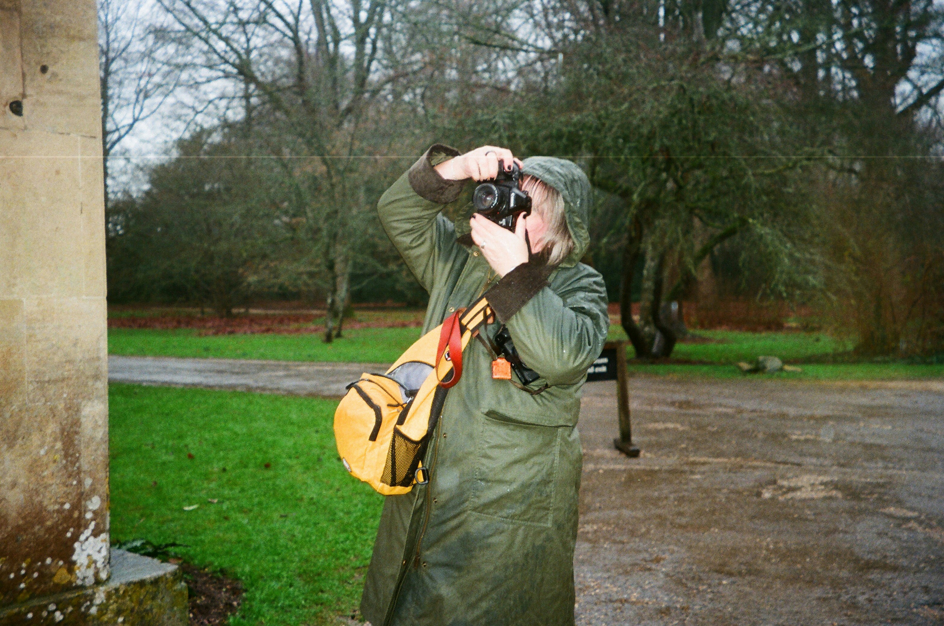Person in raincoat taking a photo outdoors