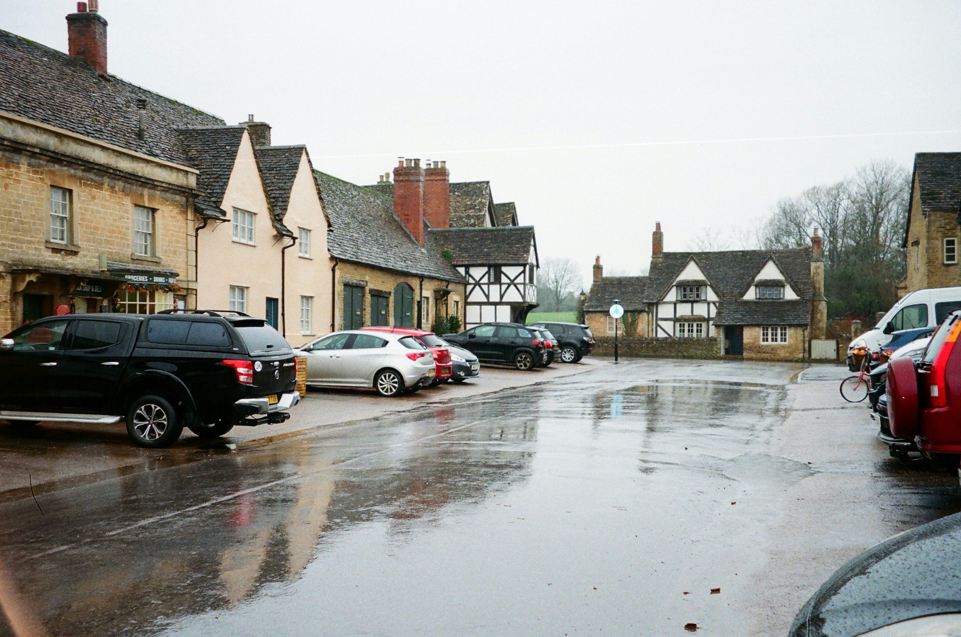 Cars parked on a wet, reflective village square