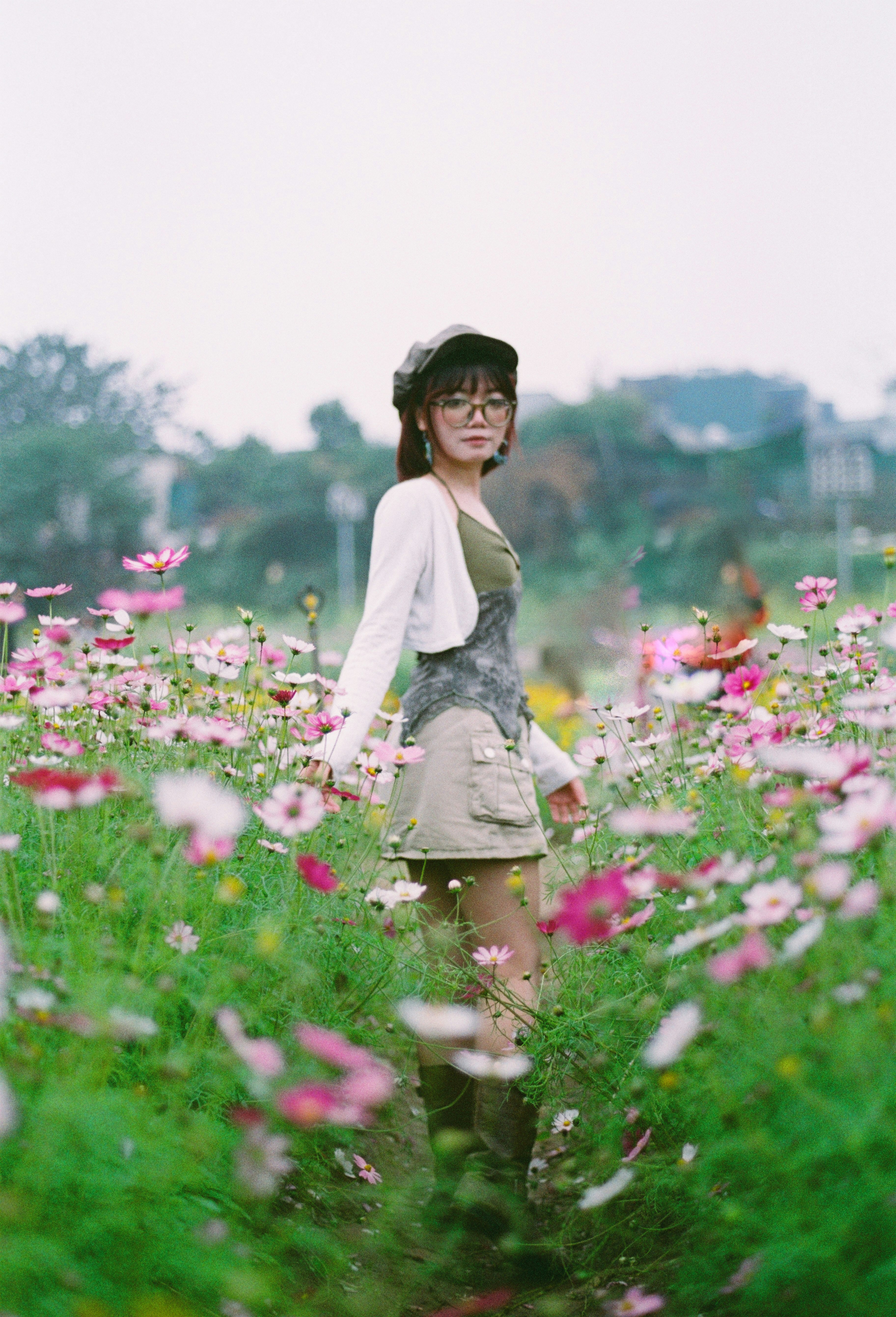 Une jeune femme traverse un champ de fleurs cosmos.