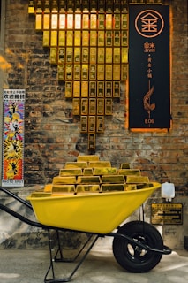 Yellow wheelbarrow overflowing with gold bars
