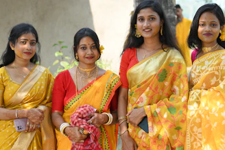 Four women in yellow and red traditional indian attire.