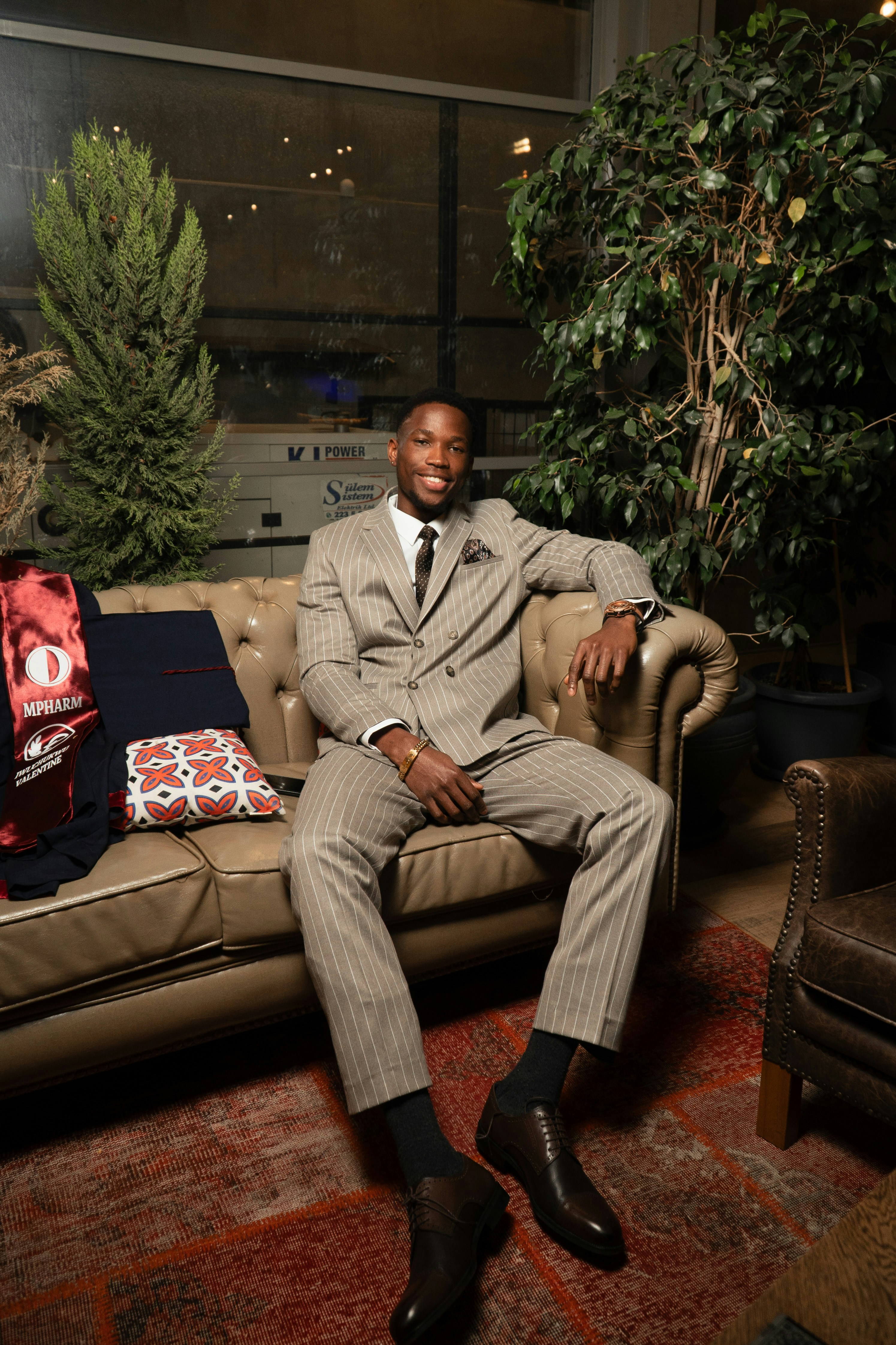 Hombre con traje de rayas sentado en un sofá de cuero.