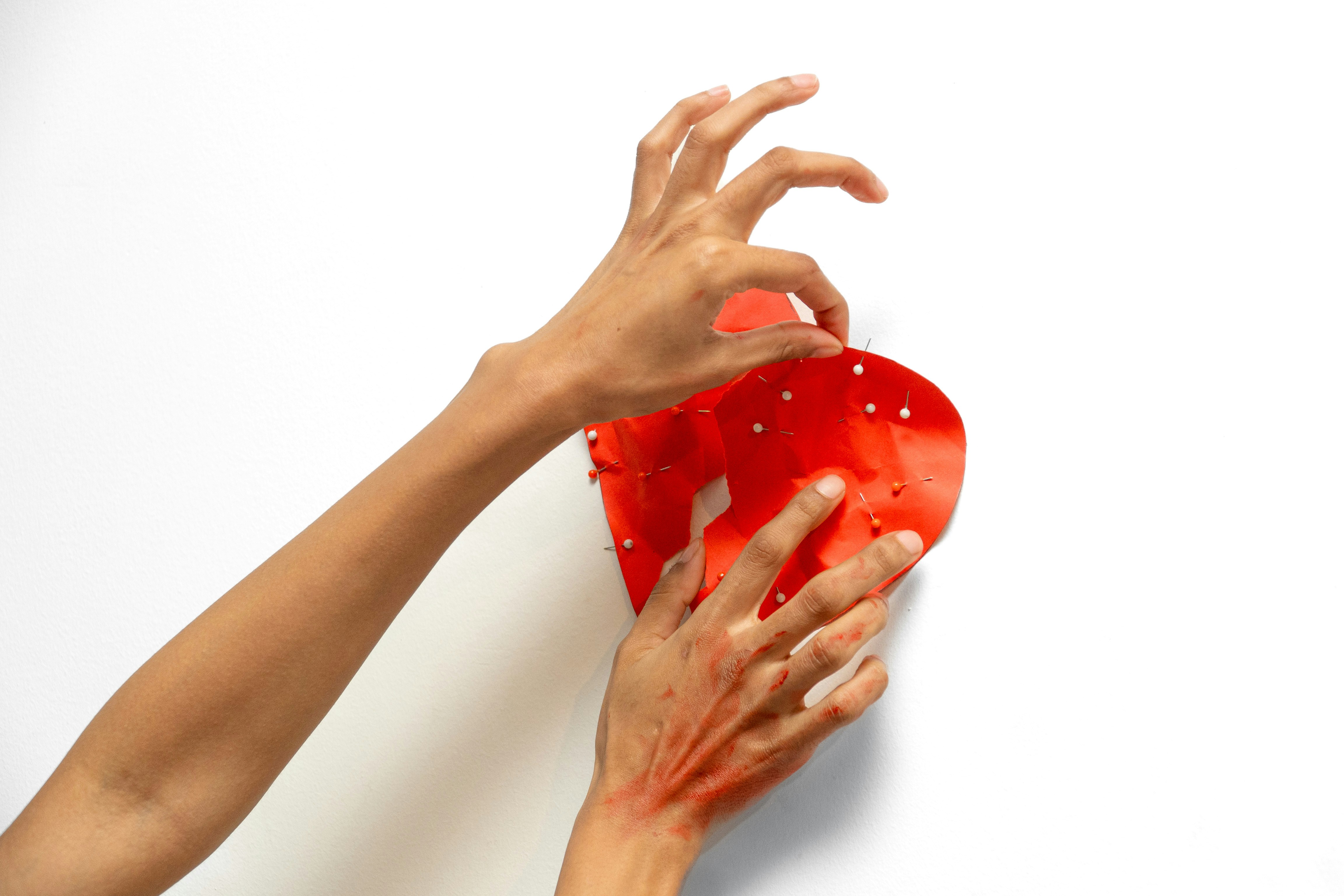 Hands arranging a red heart-shaped decoration
