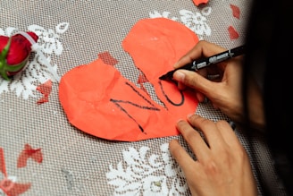 Person writing no on broken heart shape