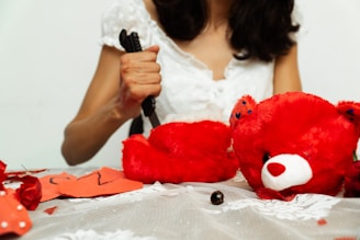Woman dismembers red teddy bear with scissors