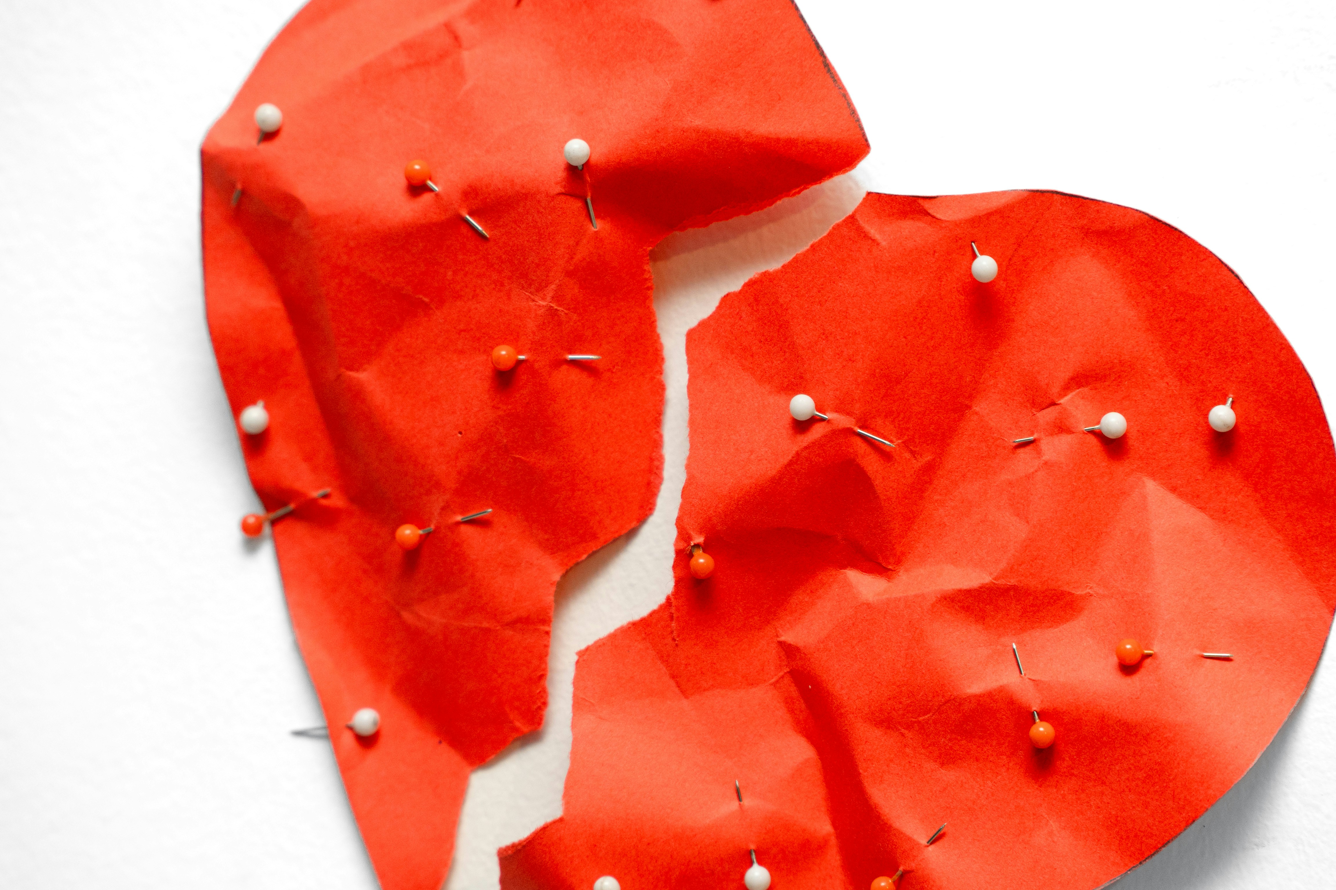 A broken red heart covered in pins