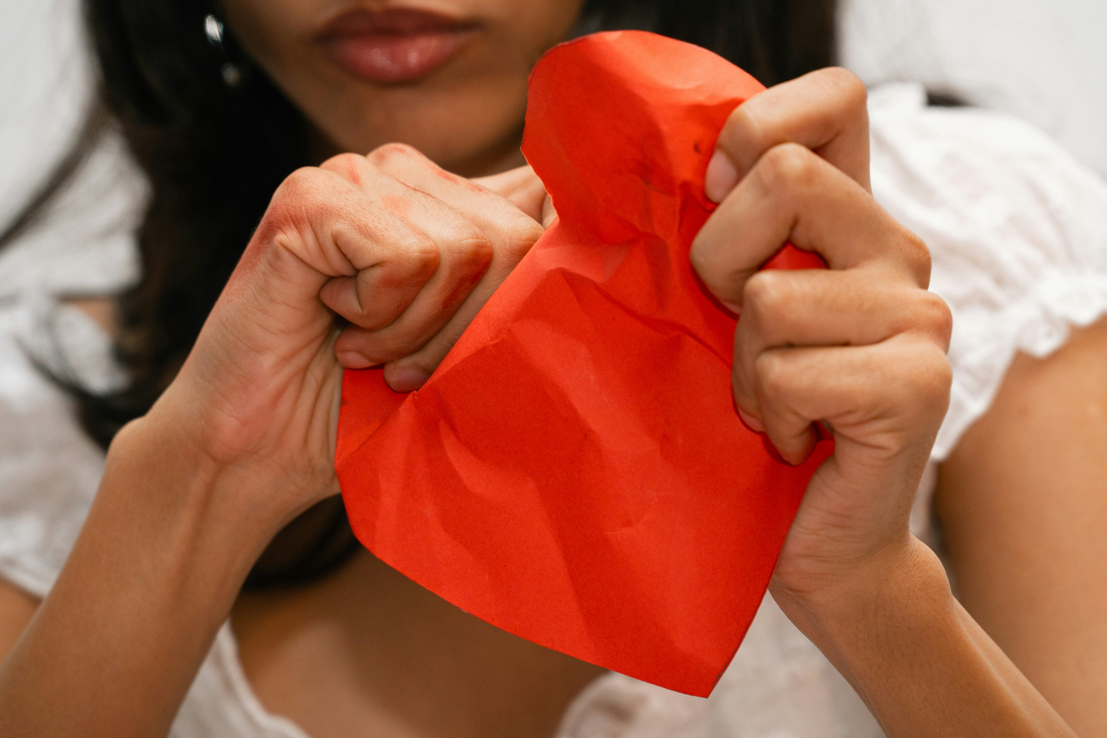 Woman tearing a red heart shape in half