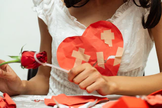 Woman holding a red rose and a broken heart