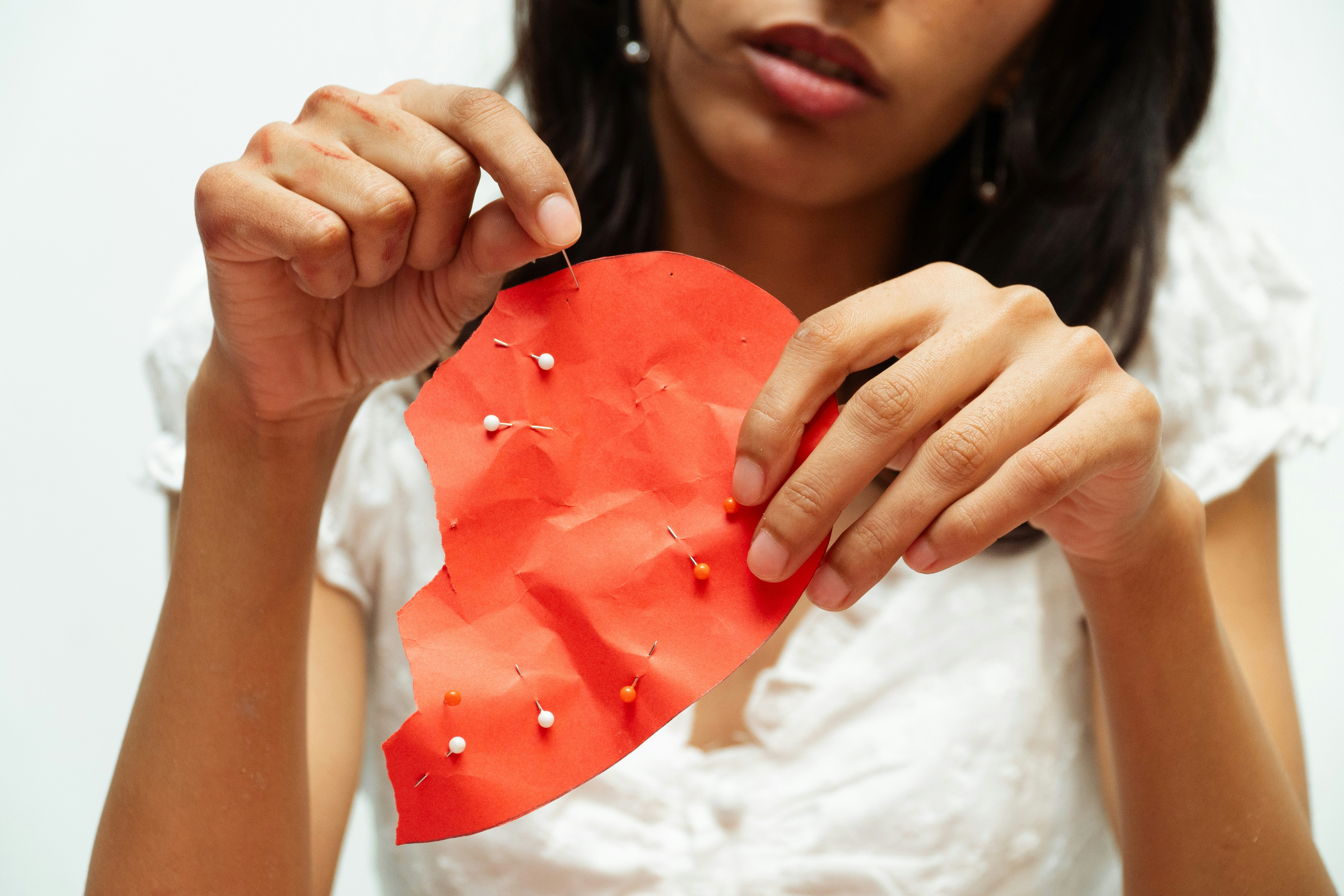 Woman pinning together a torn red heart
