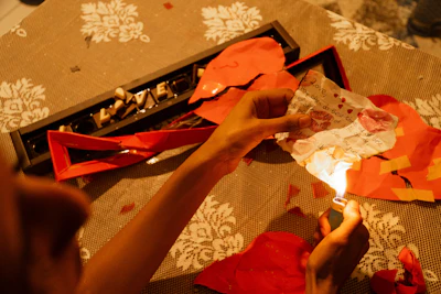 Person lighting a red paper lantern with a lighter.