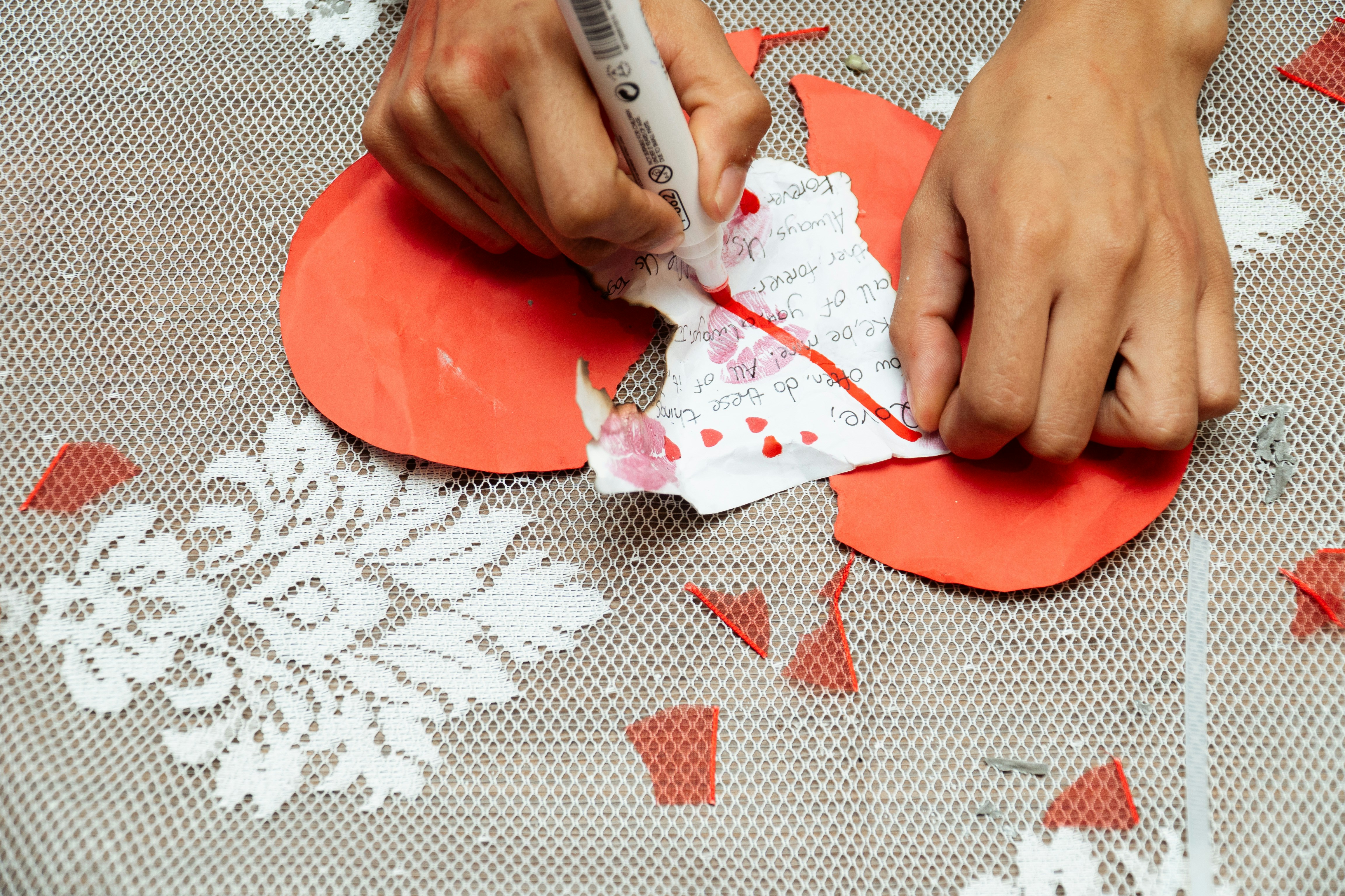 Hands drawing on red paper with marker