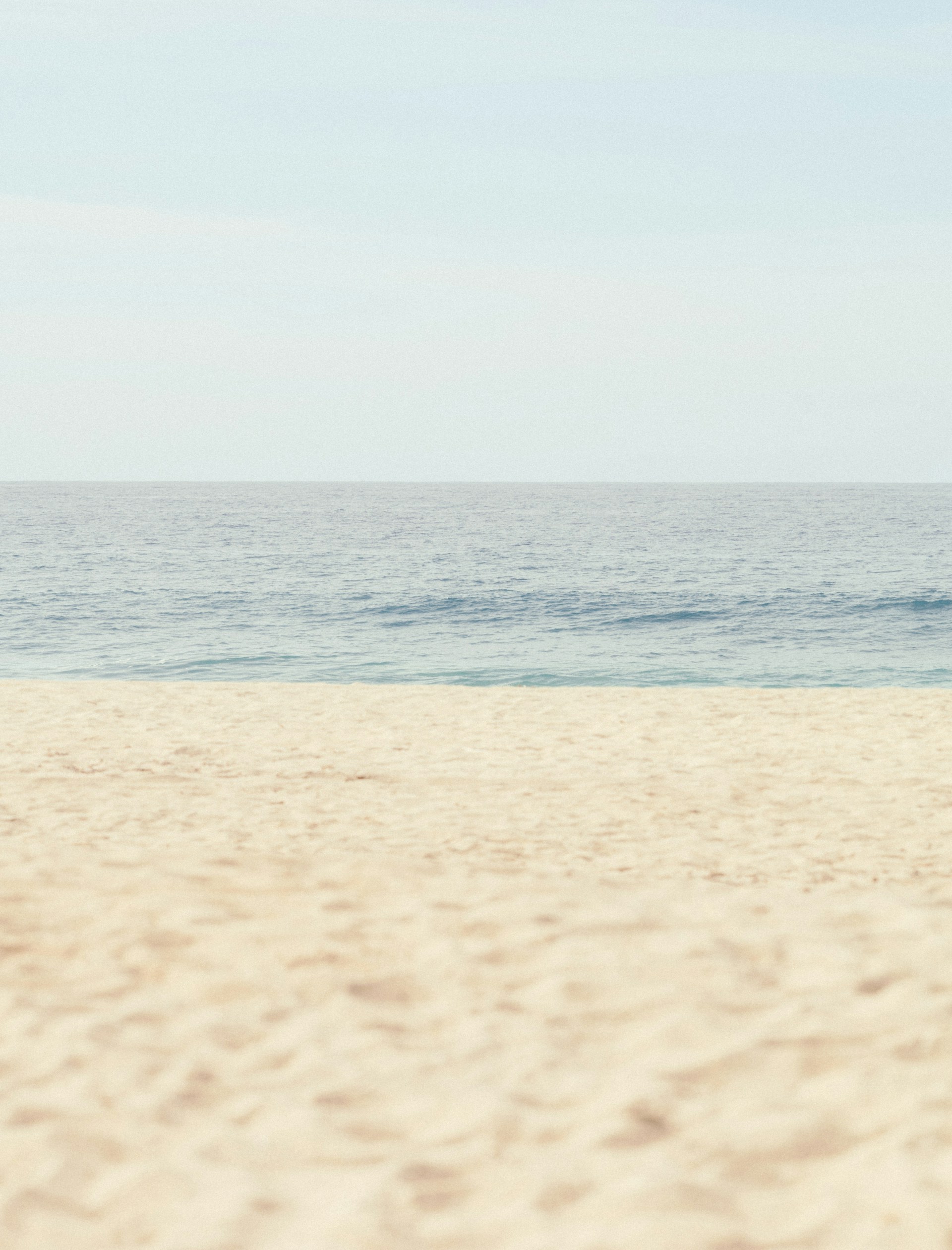 Calm ocean meets a sandy beach under clear sky