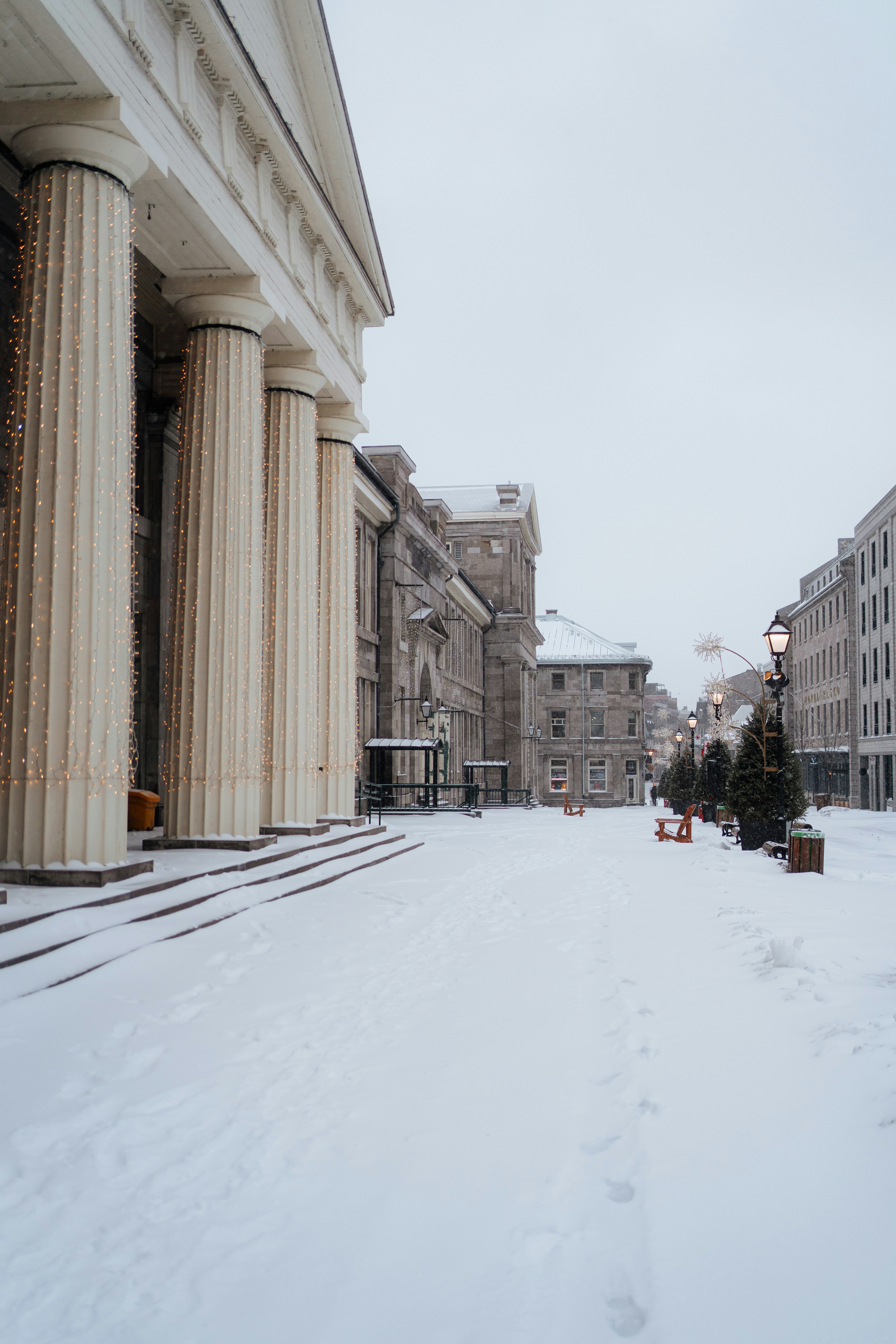 A snow-covered street with large columns and buildings.