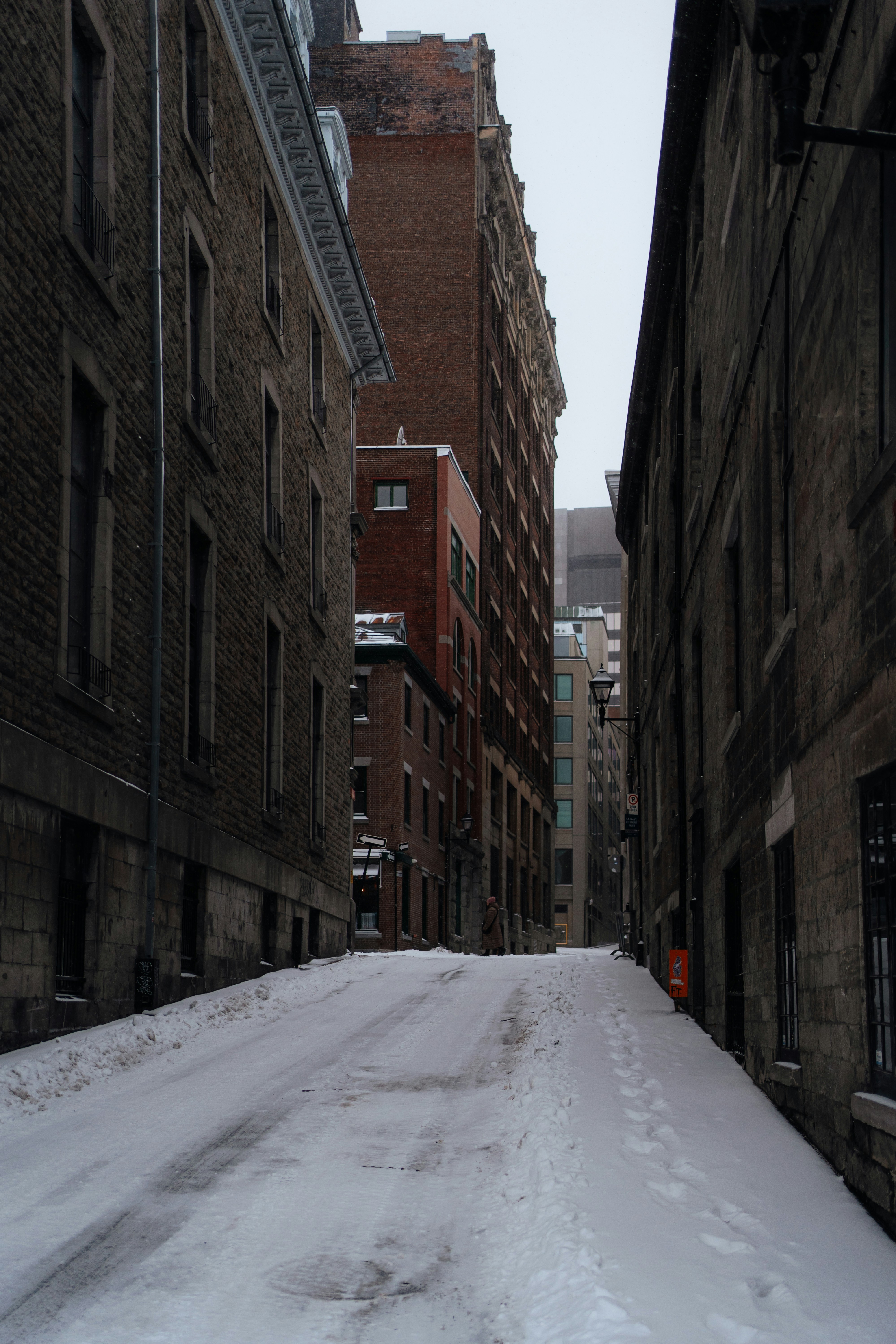 Snowy alley between old brick buildings
