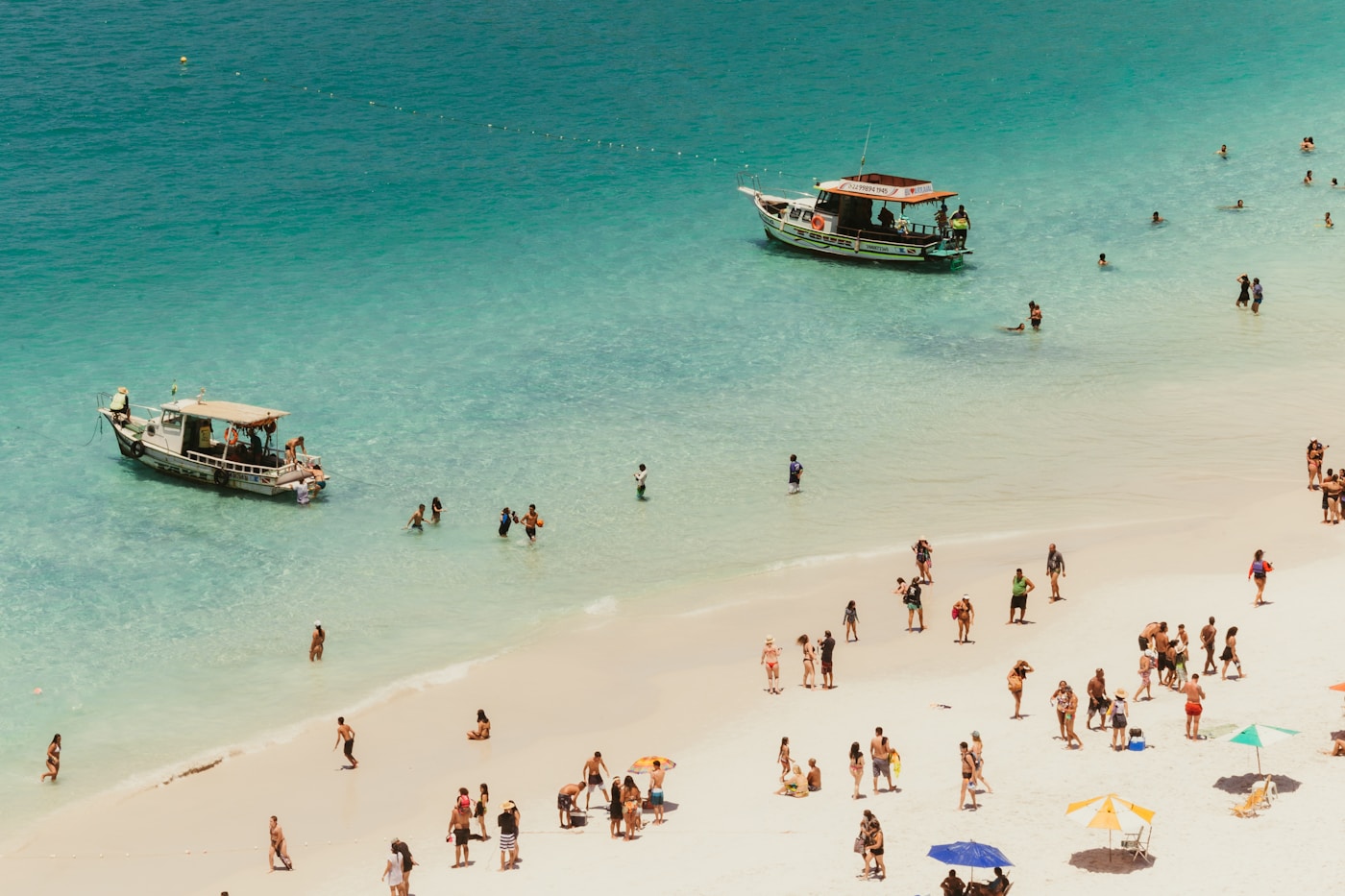 Two wooden boats moored off a white sand beach
