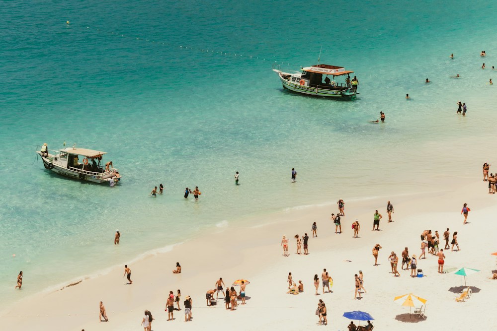 Two wooden boats moored off a white sand beach