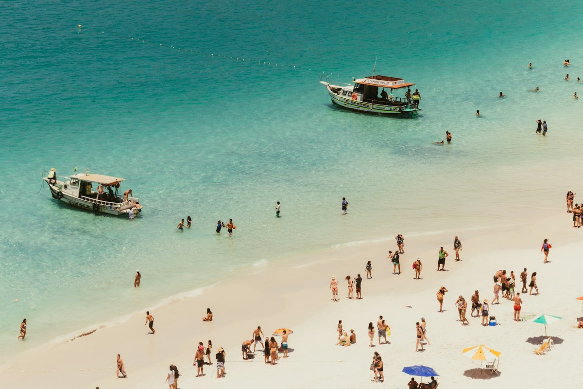 Two wooden boats moored off a white sand beach