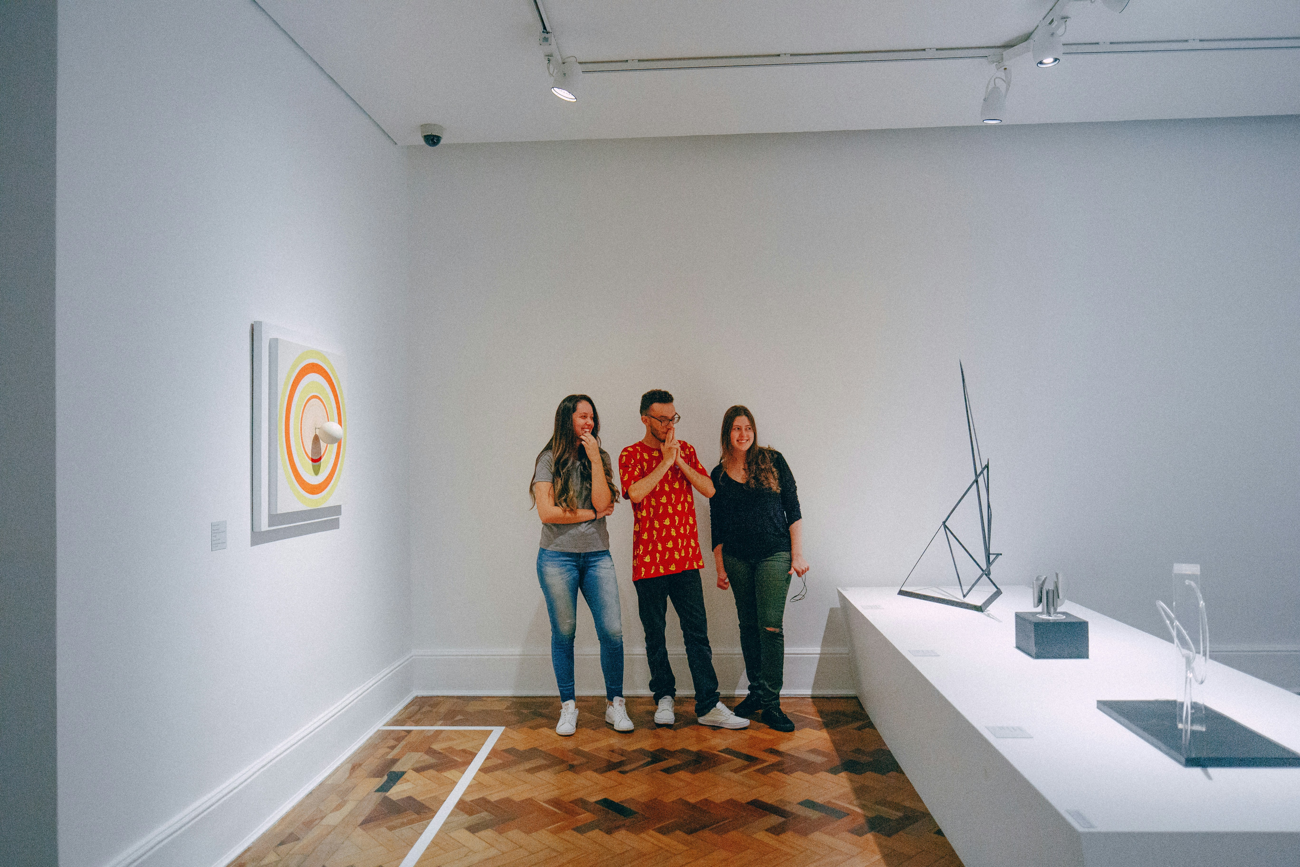 Three people looking at art in a gallery.