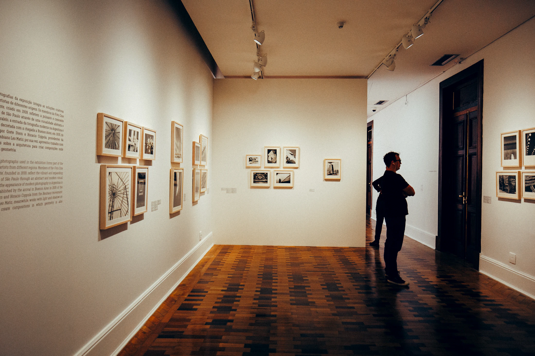 Visitor considering framed photographic works in a warmly lit gallery