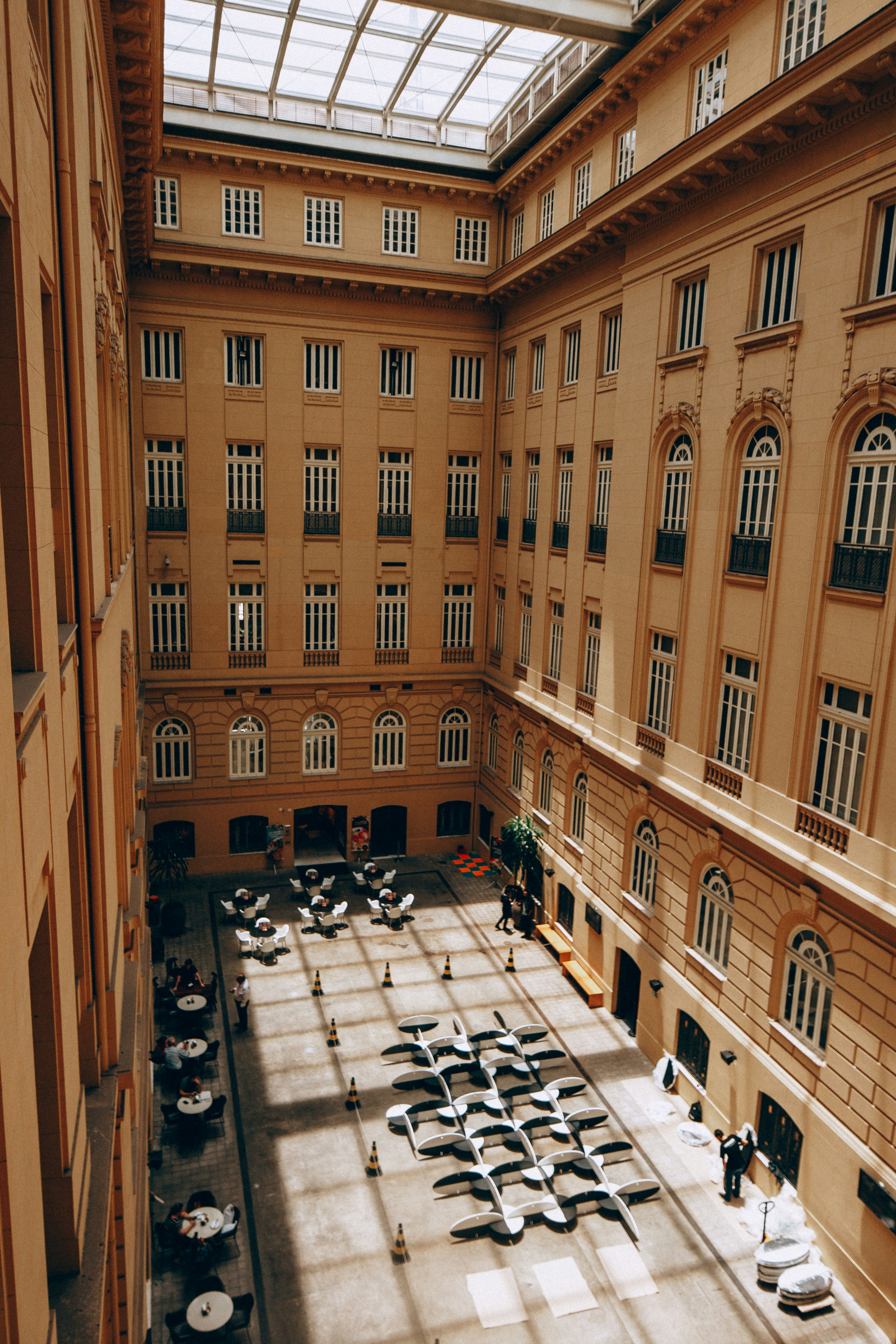 큰 건물의 안뜰에 테이블과 의자가 놓여 있습니다.