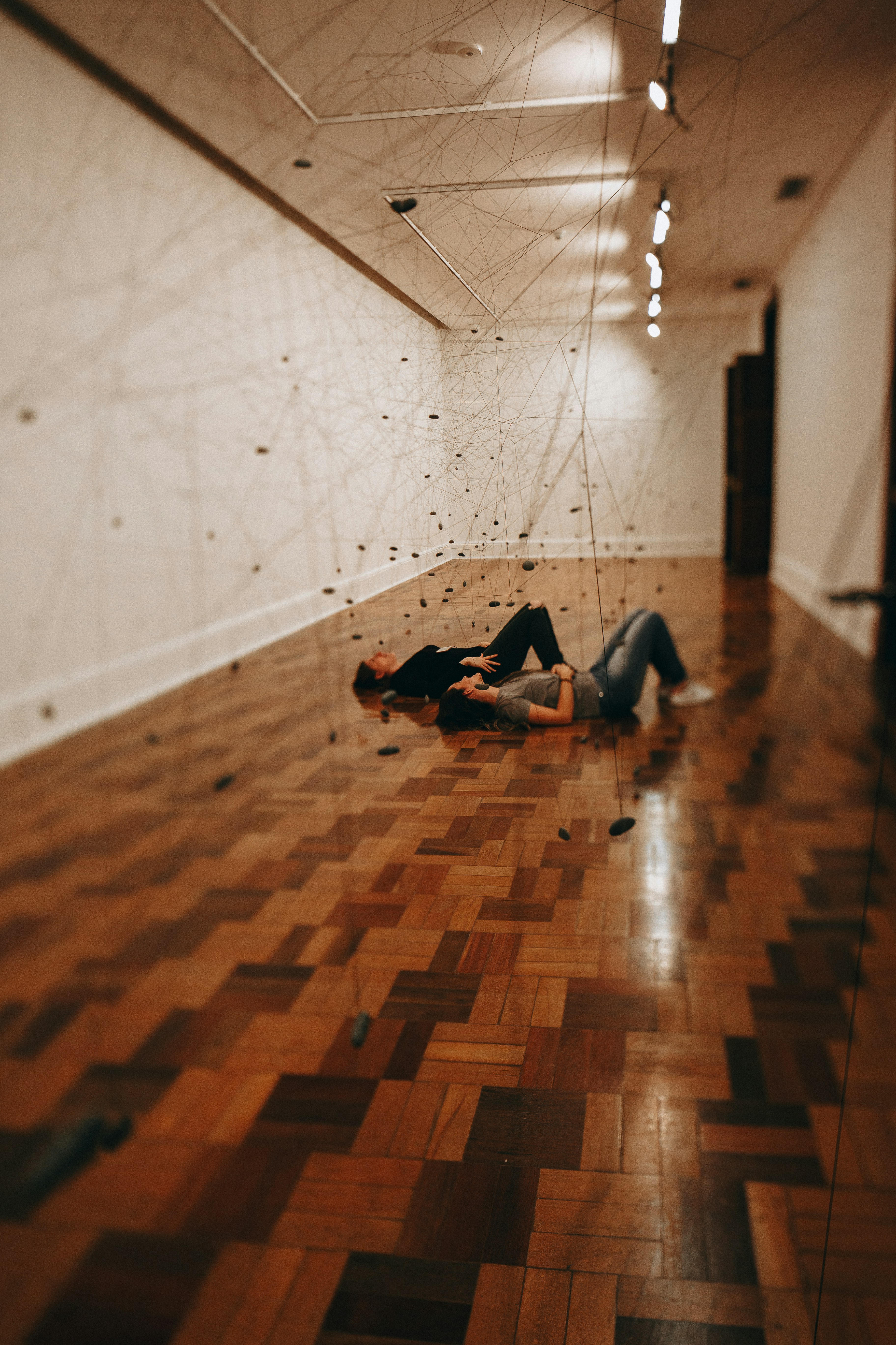 두 사람이 반짝이는 나무 바닥에 누워 있다.