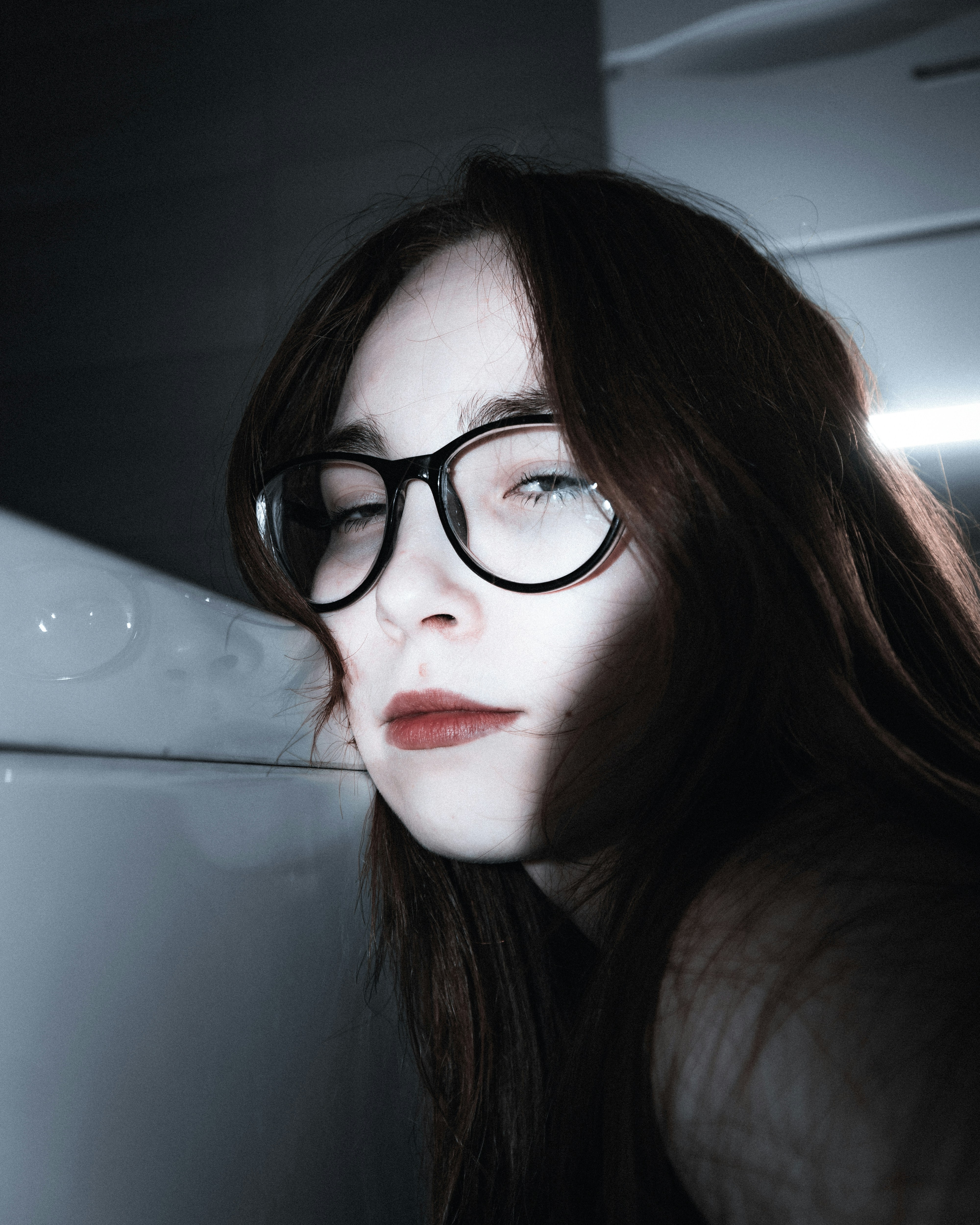 Young woman with glasses and red lipstick looks away