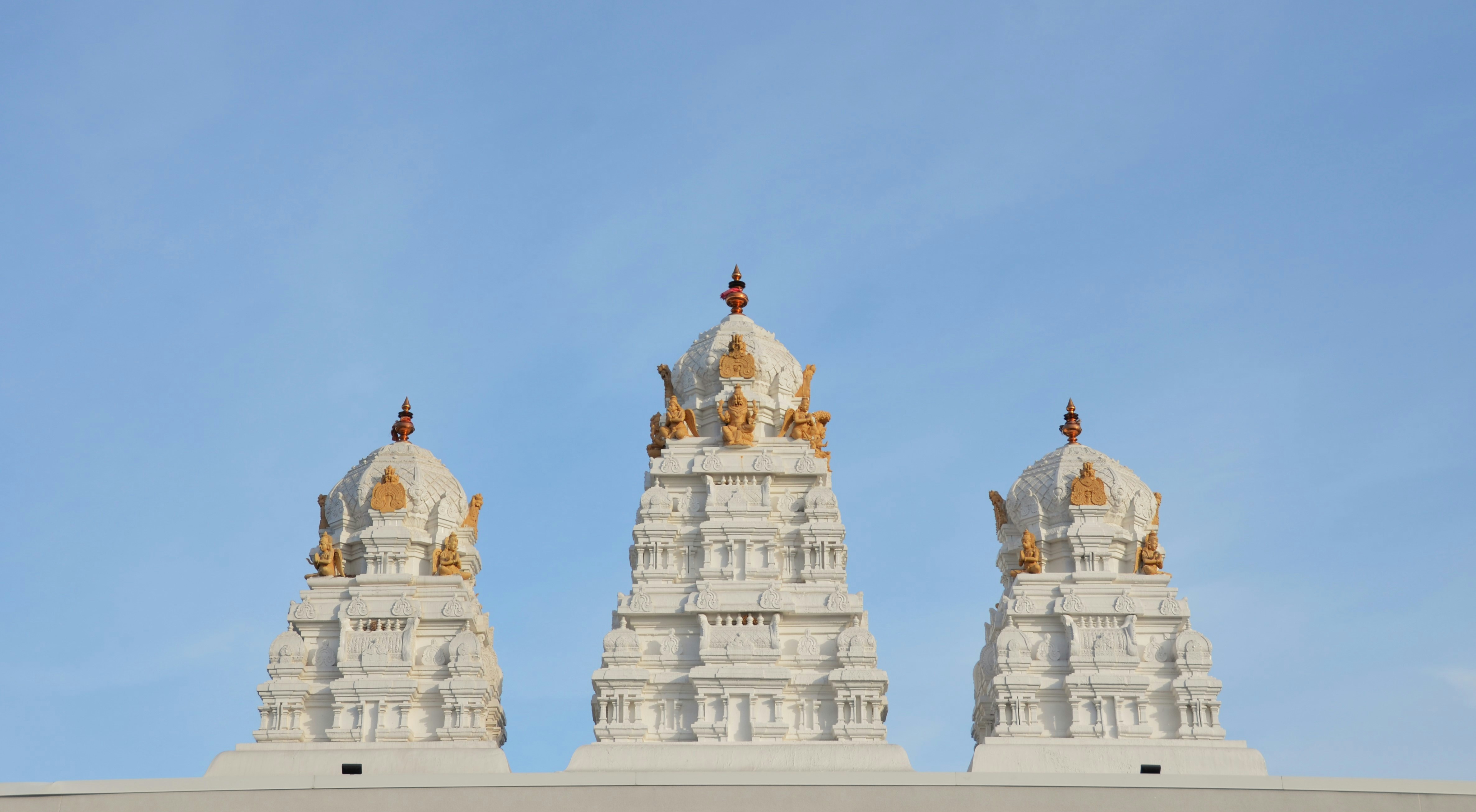 Three ornate white temple towers against a blue sky