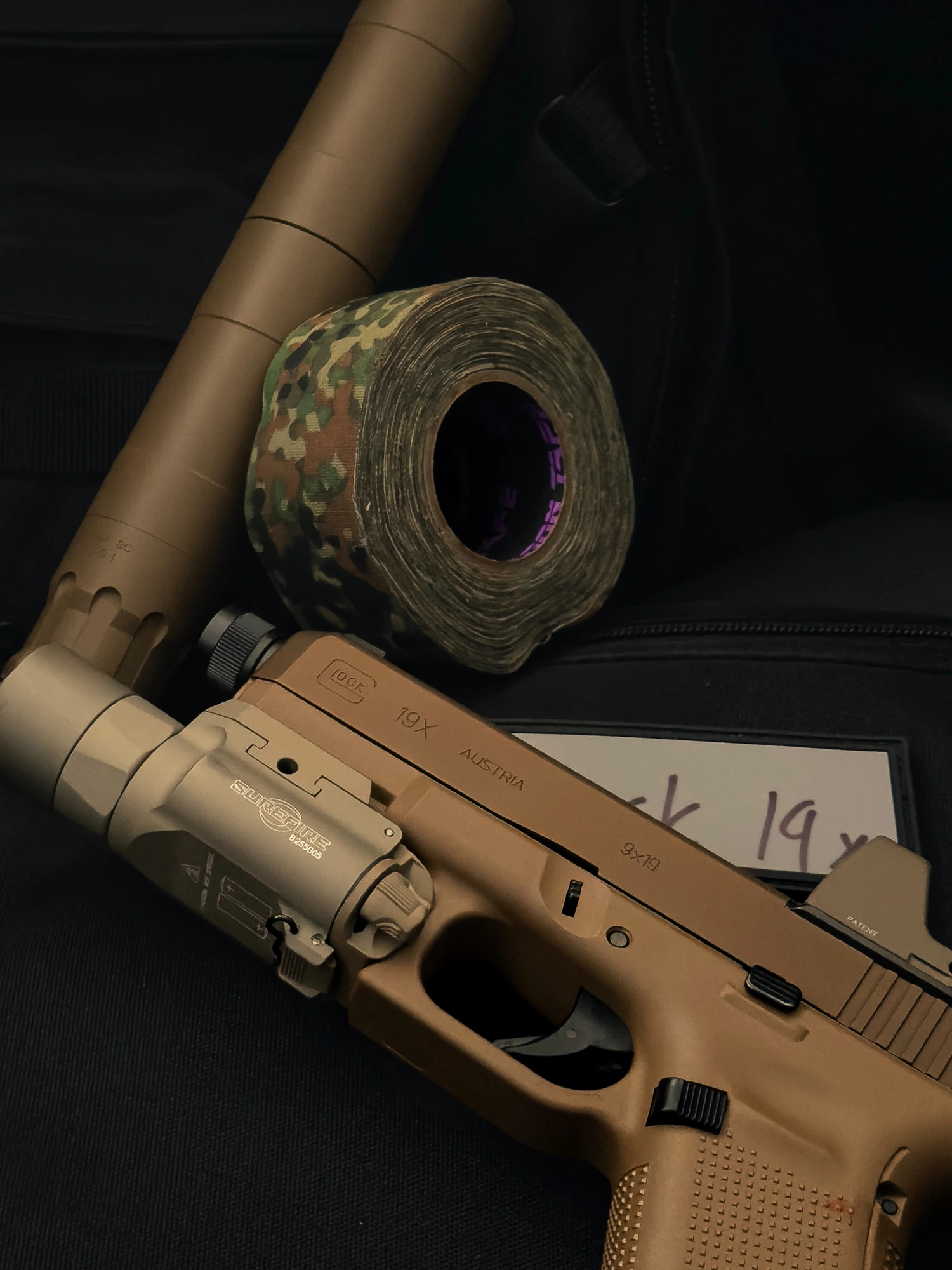 Tan pistol fitted with a suppressor