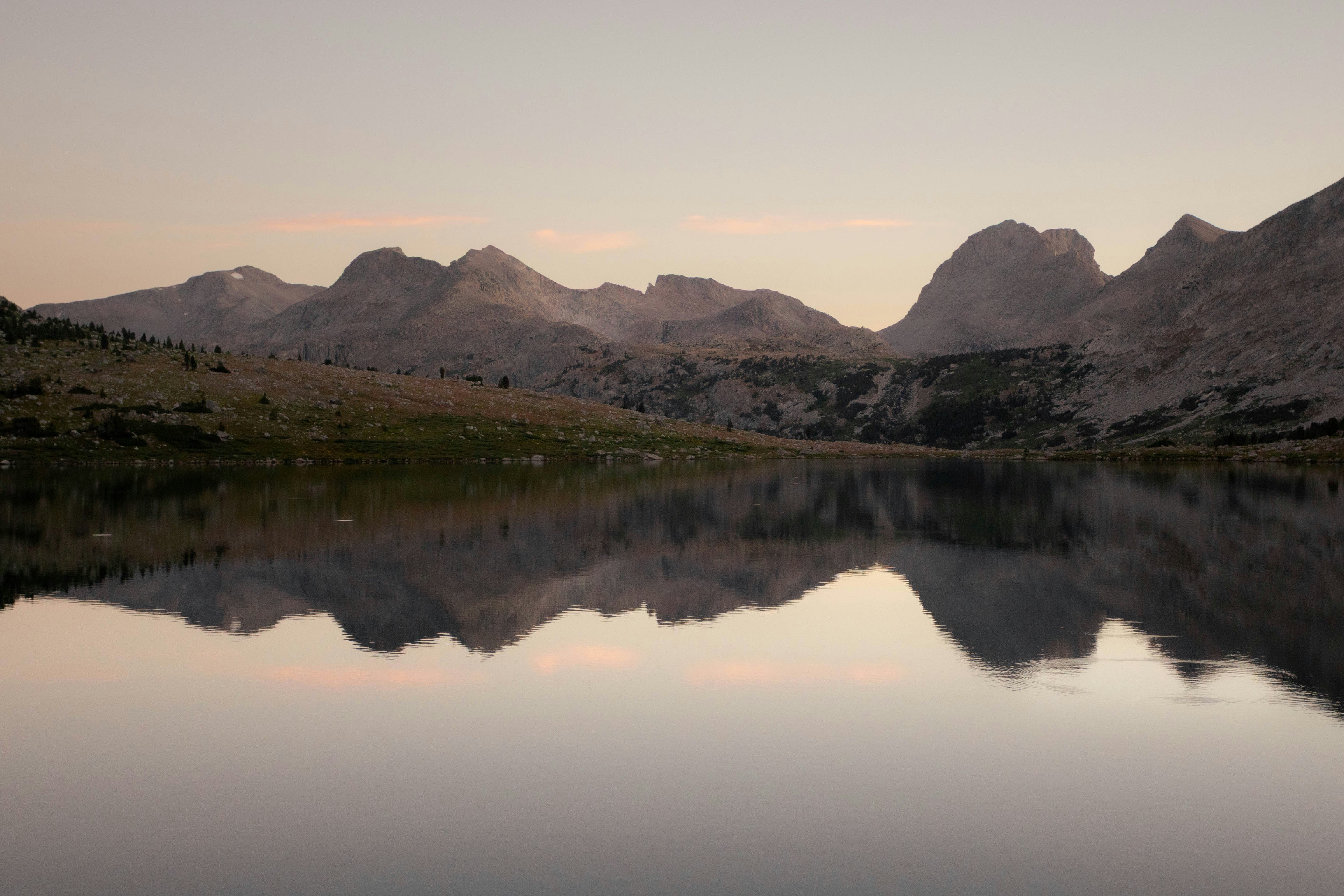 Mountain range reflected in a calm lake at dusk.