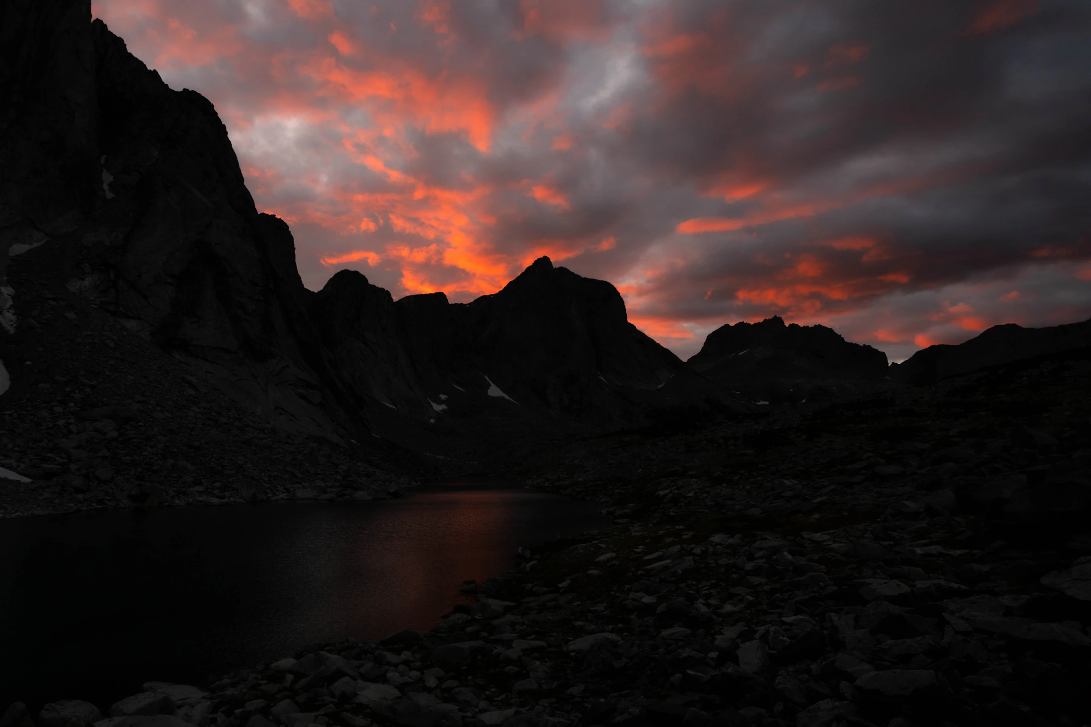 Last light burning red over a granite cirque and an alpine lake in the Wind River Range