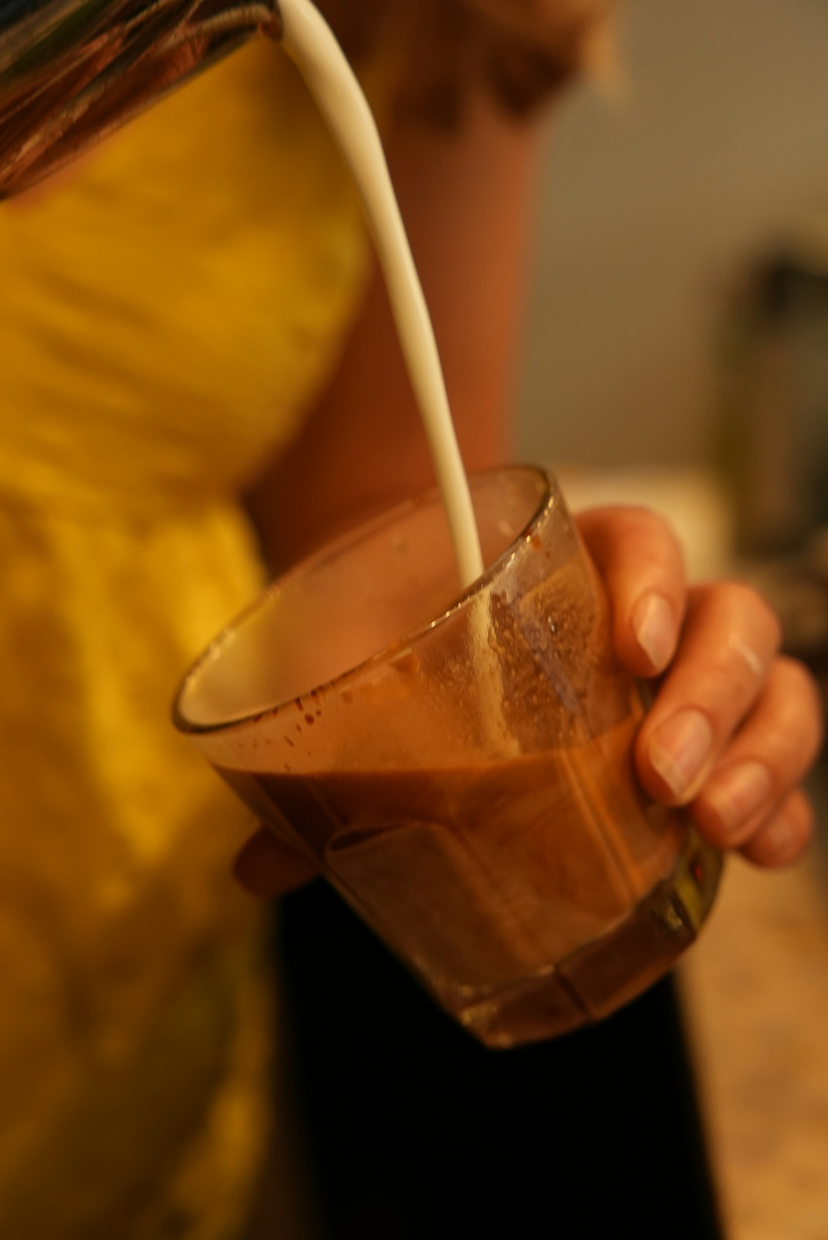 Milk being poured into a glass of coffee.