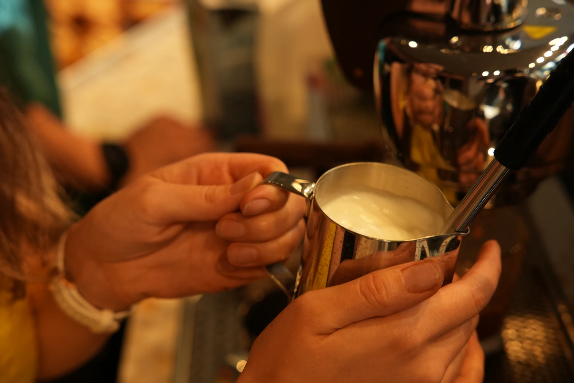 Barista steaming milk in a metal pitcher